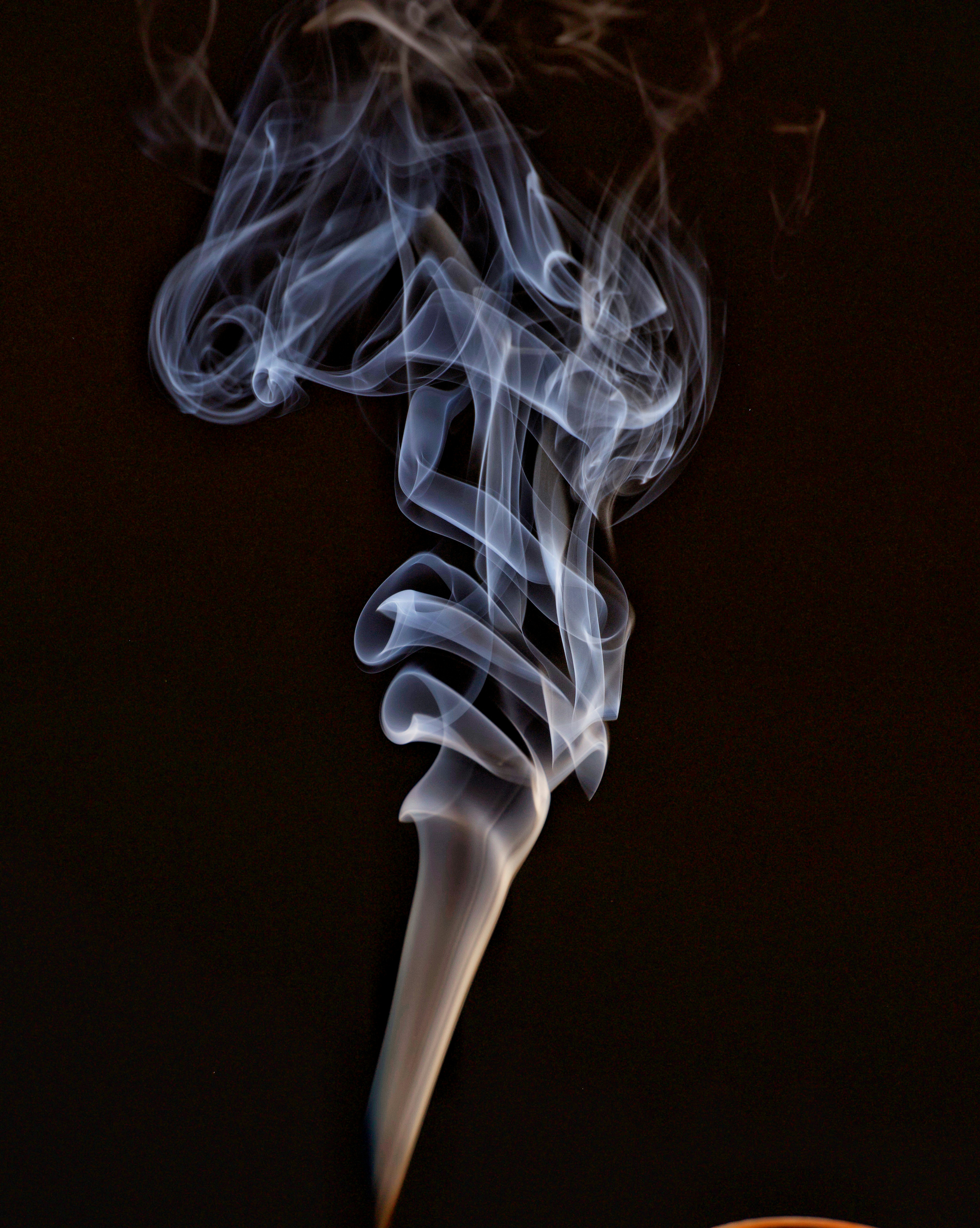 Wisps of smoke curl upwards against a dark background.