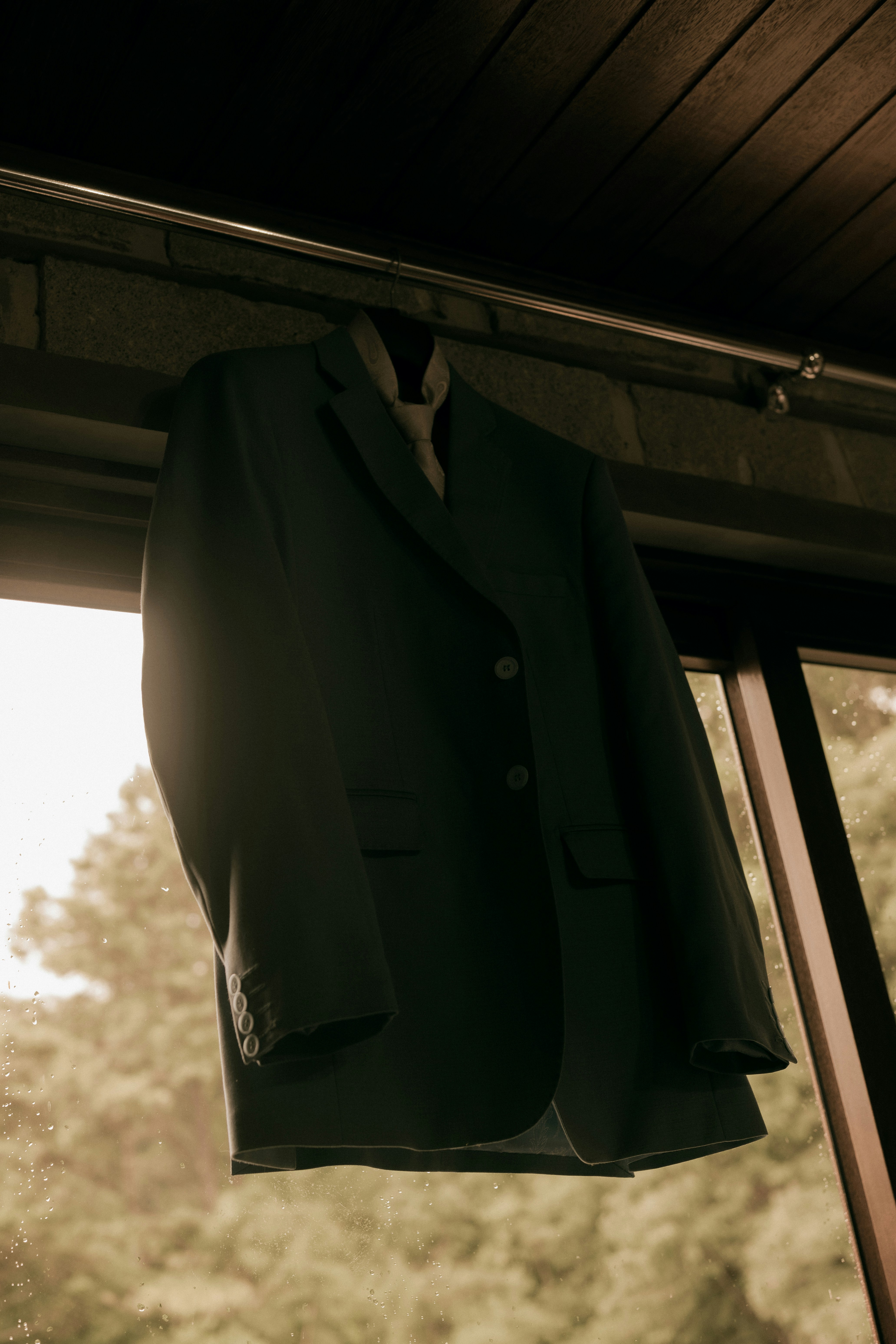 Ein dunkles Jackett hängt an einem Fenster.