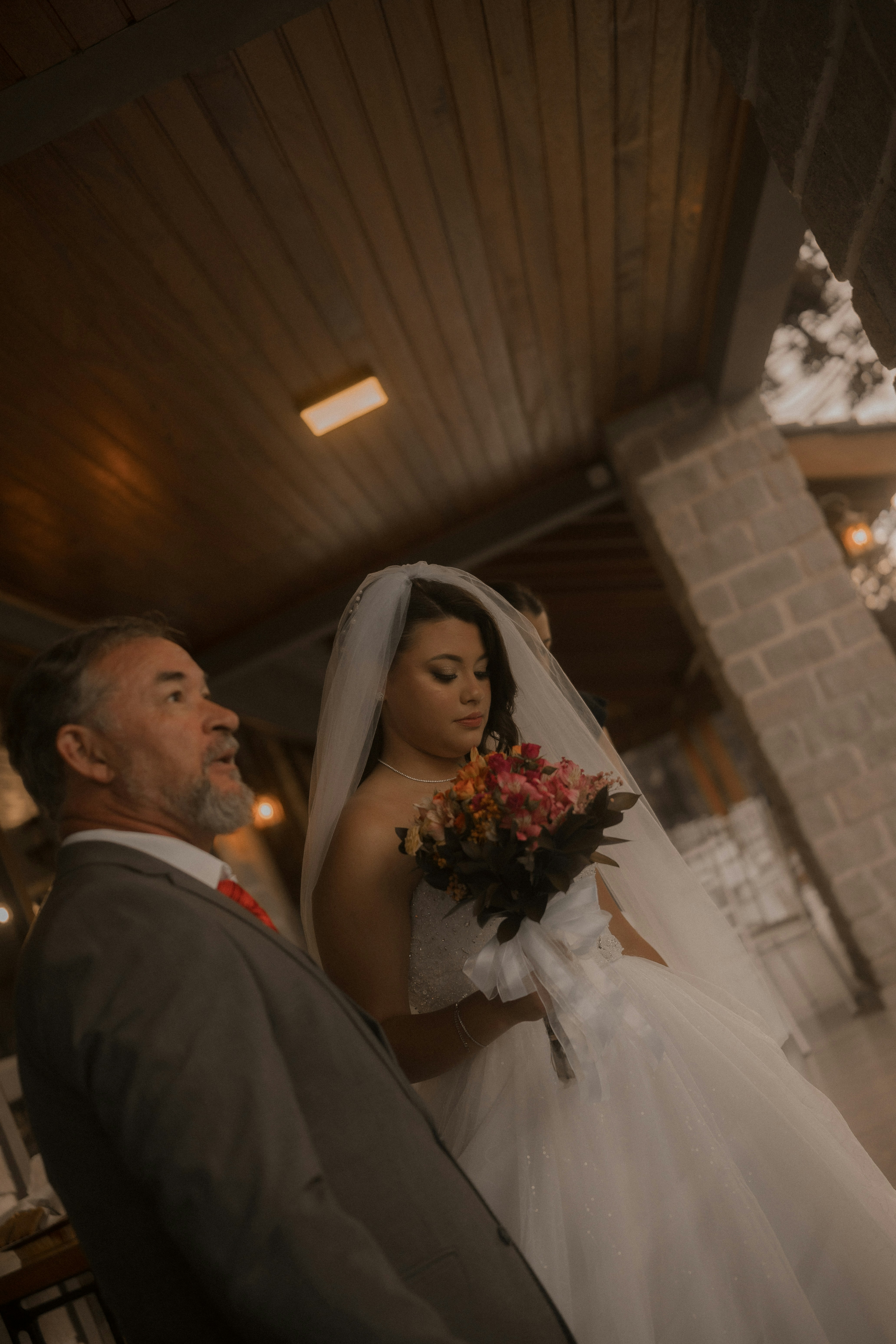 Braut mit Schleier hält den Blumenstrauß mit dem Vater