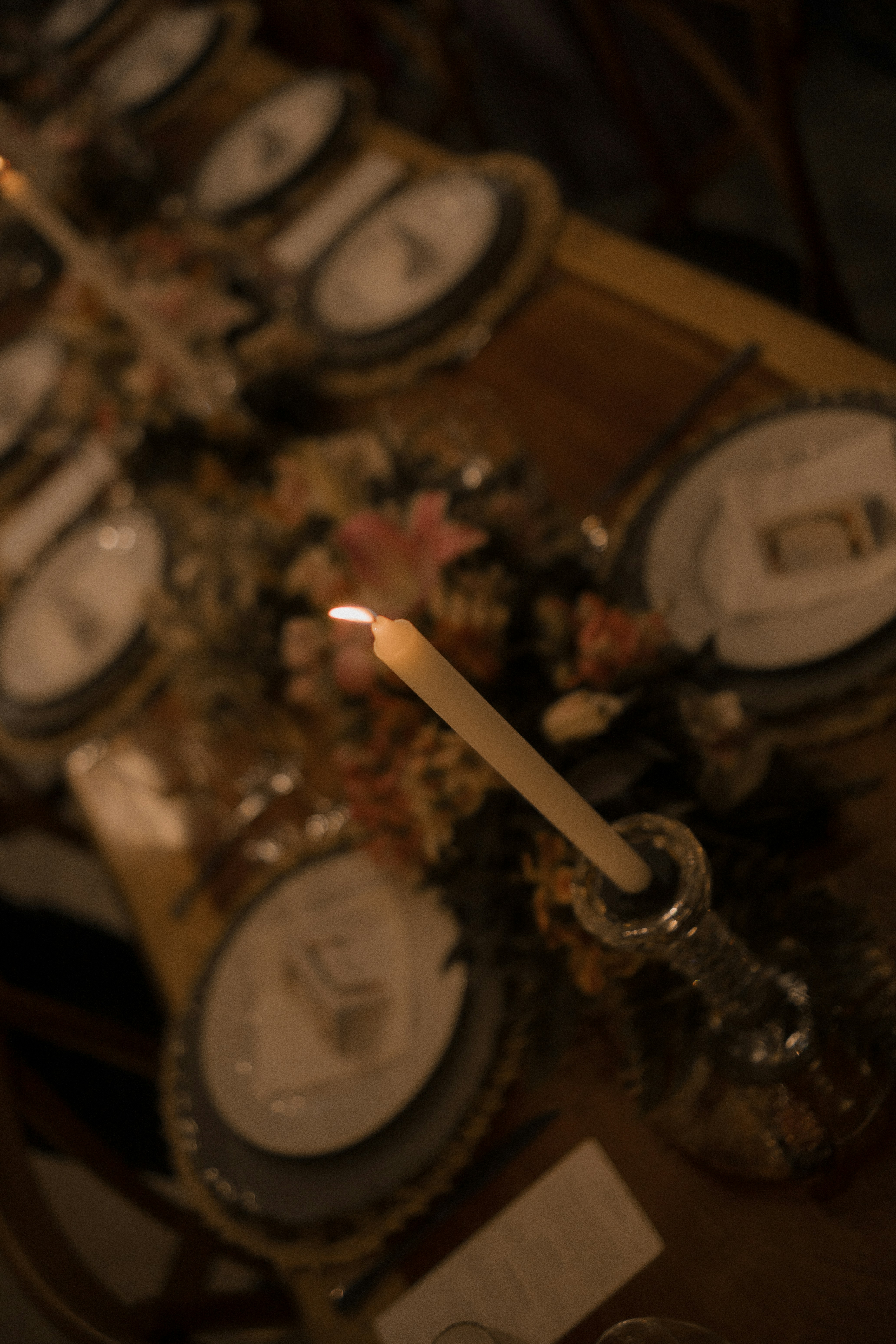 A candle illuminates a formal dinner table setting.
