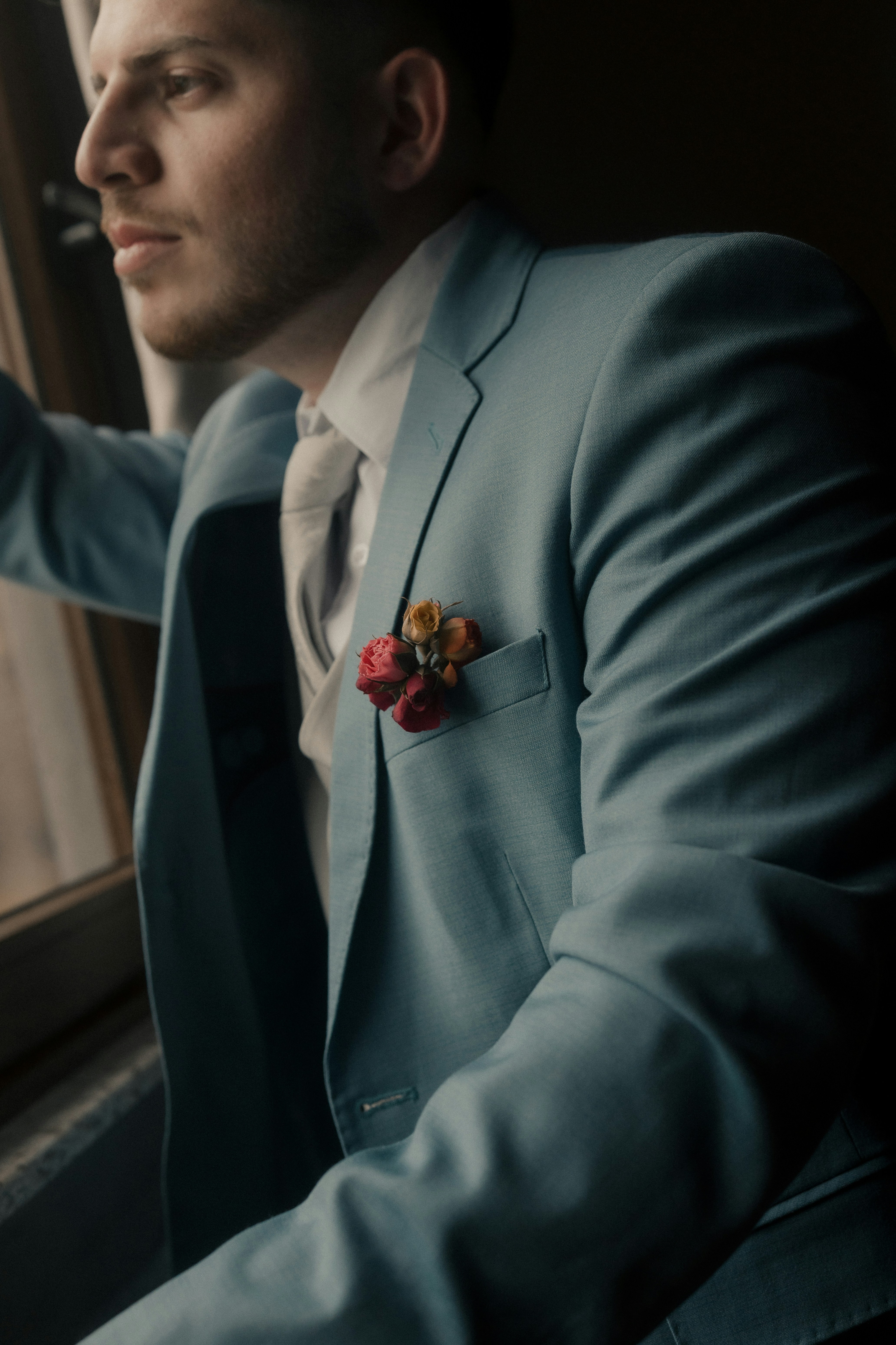 Mann im hellblauen Anzug blickt aus dem Fenster