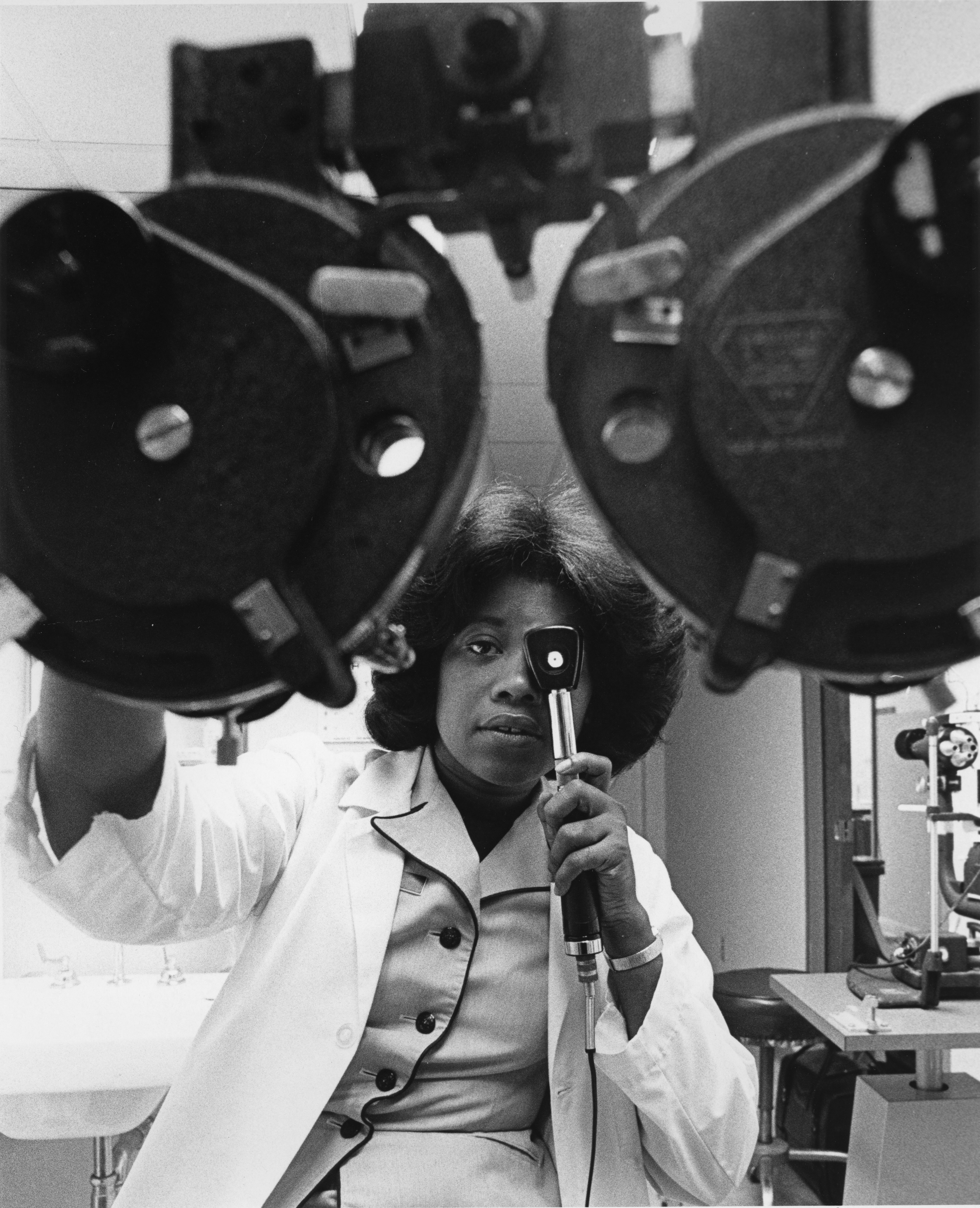 Ophthalmologist examines patient's eye with instrument.