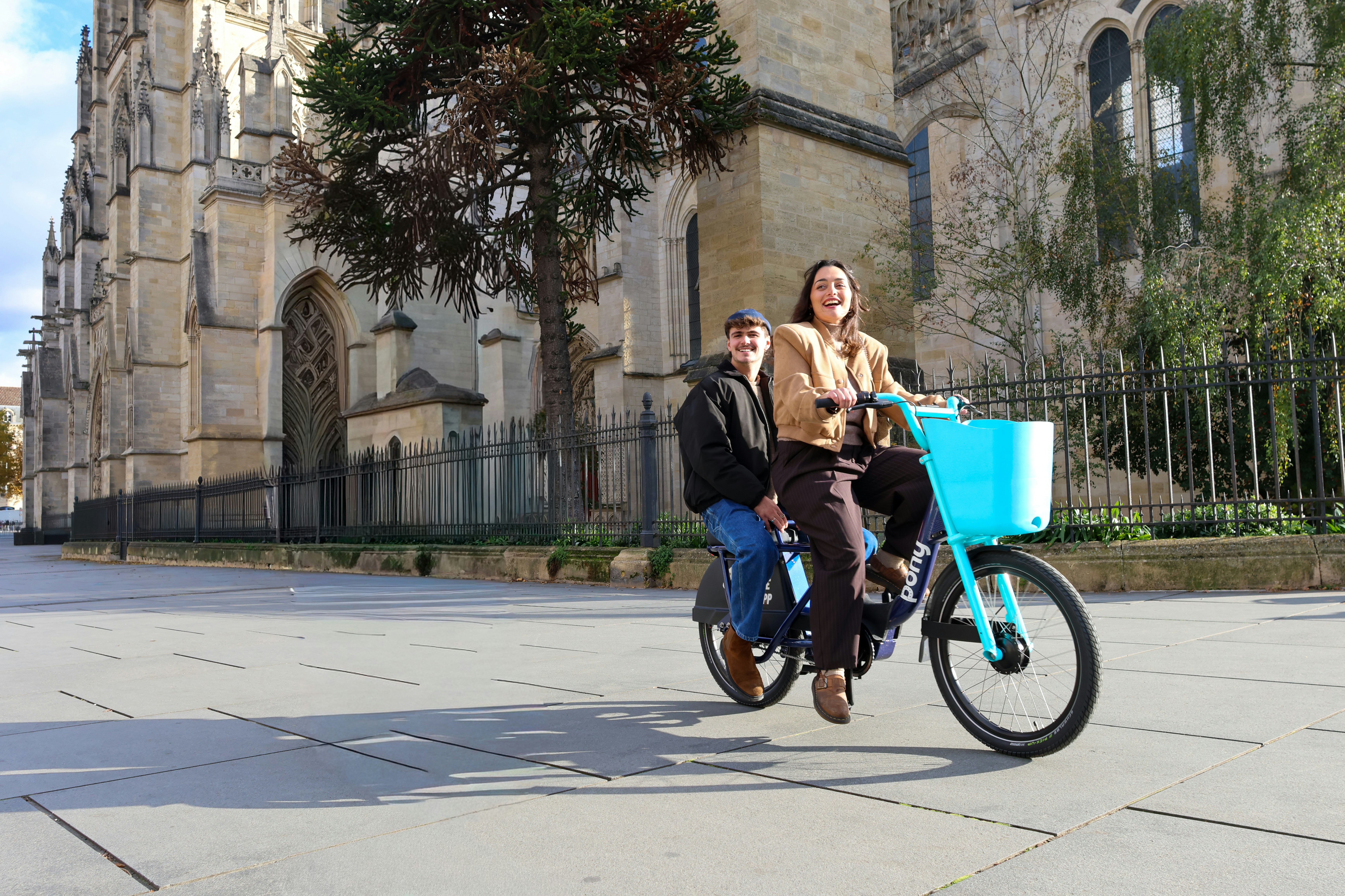 Two people riding a tandem bicycle in a city
