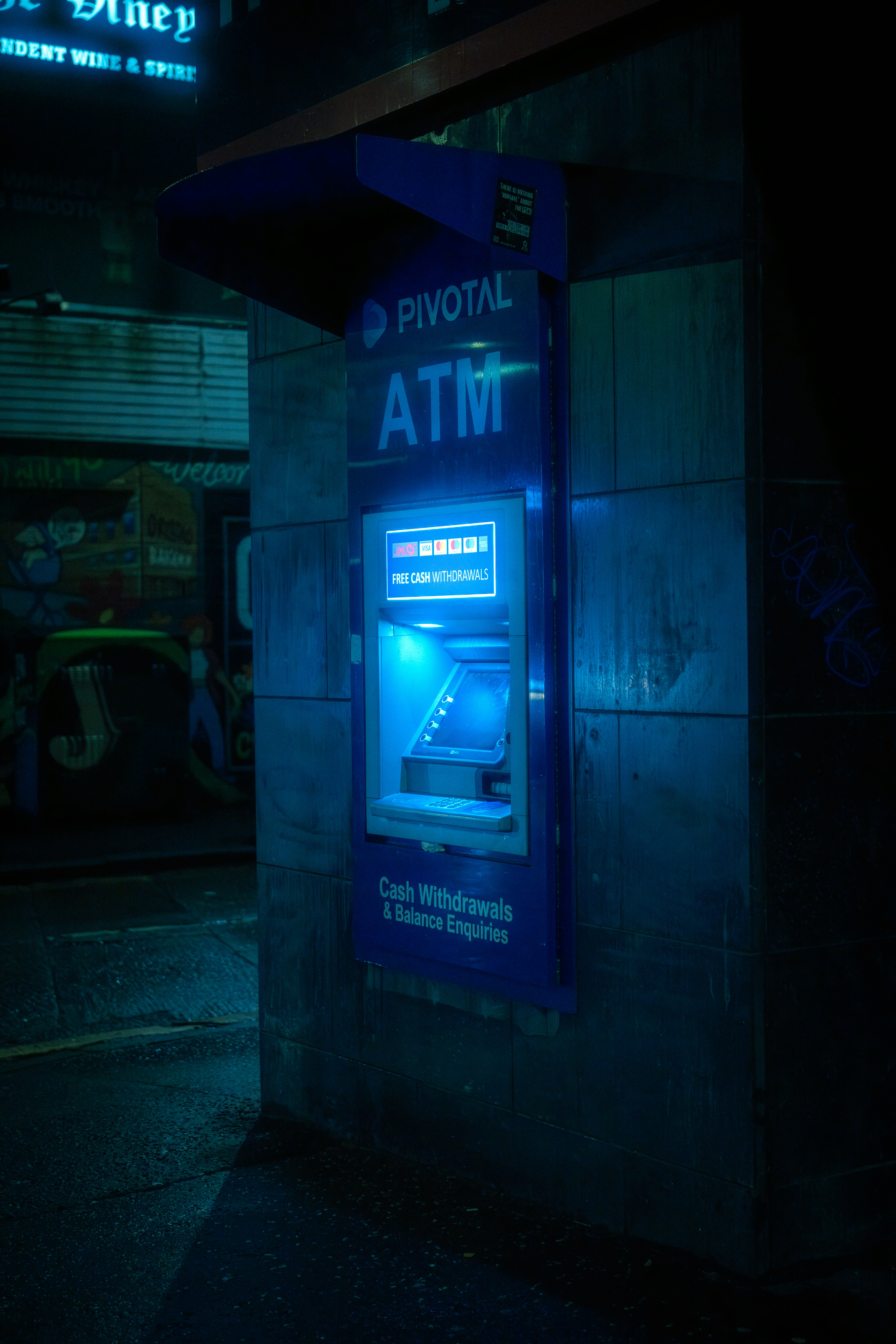 Blue atm machine glows brightly at night.
