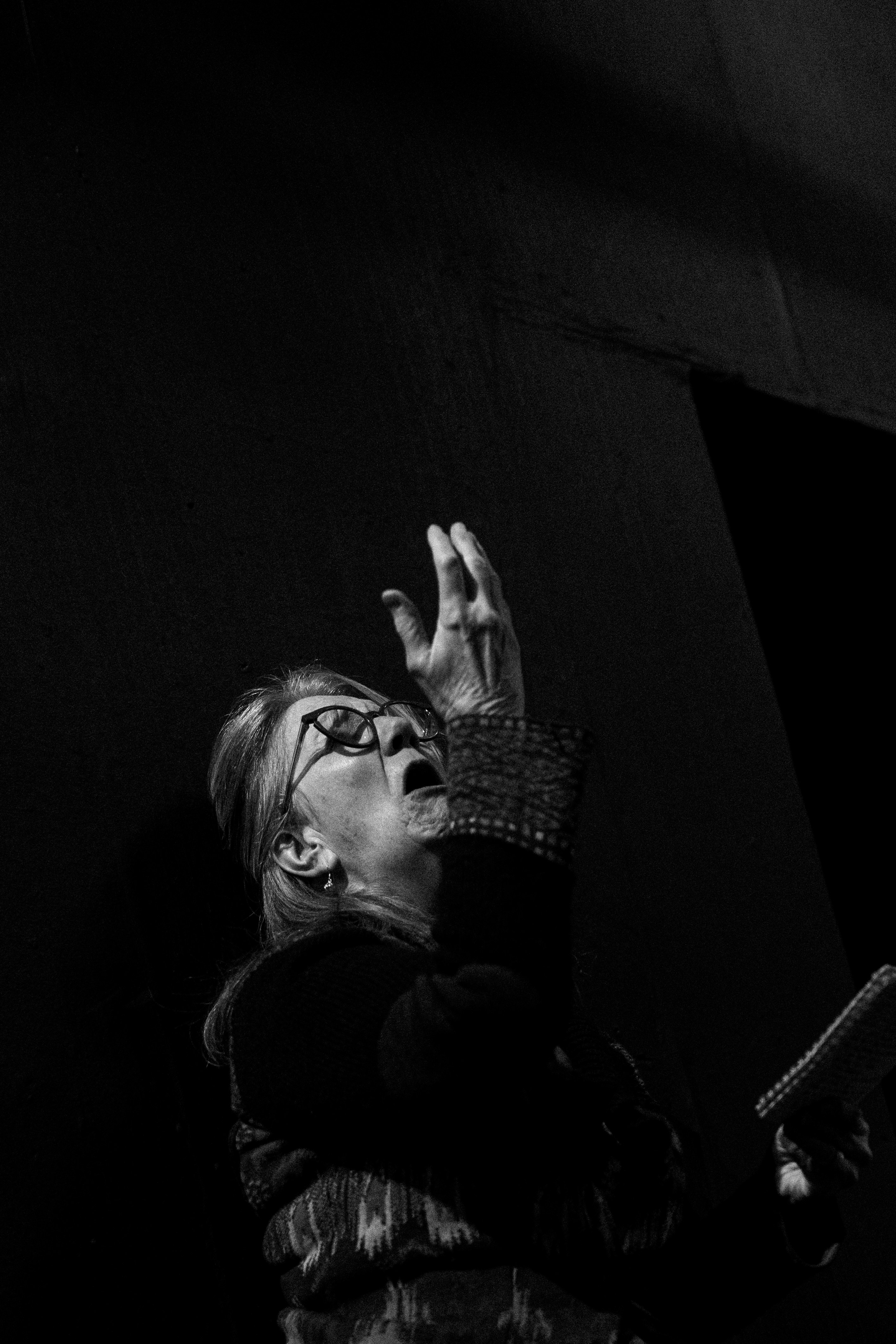 Femme âgée avec des lunettes qui lève la bouche ouverte.