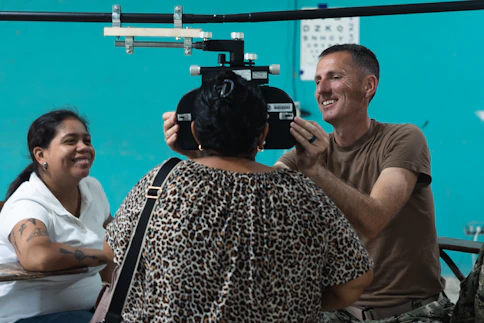 Optometrist examines patient's eyes with equipment.