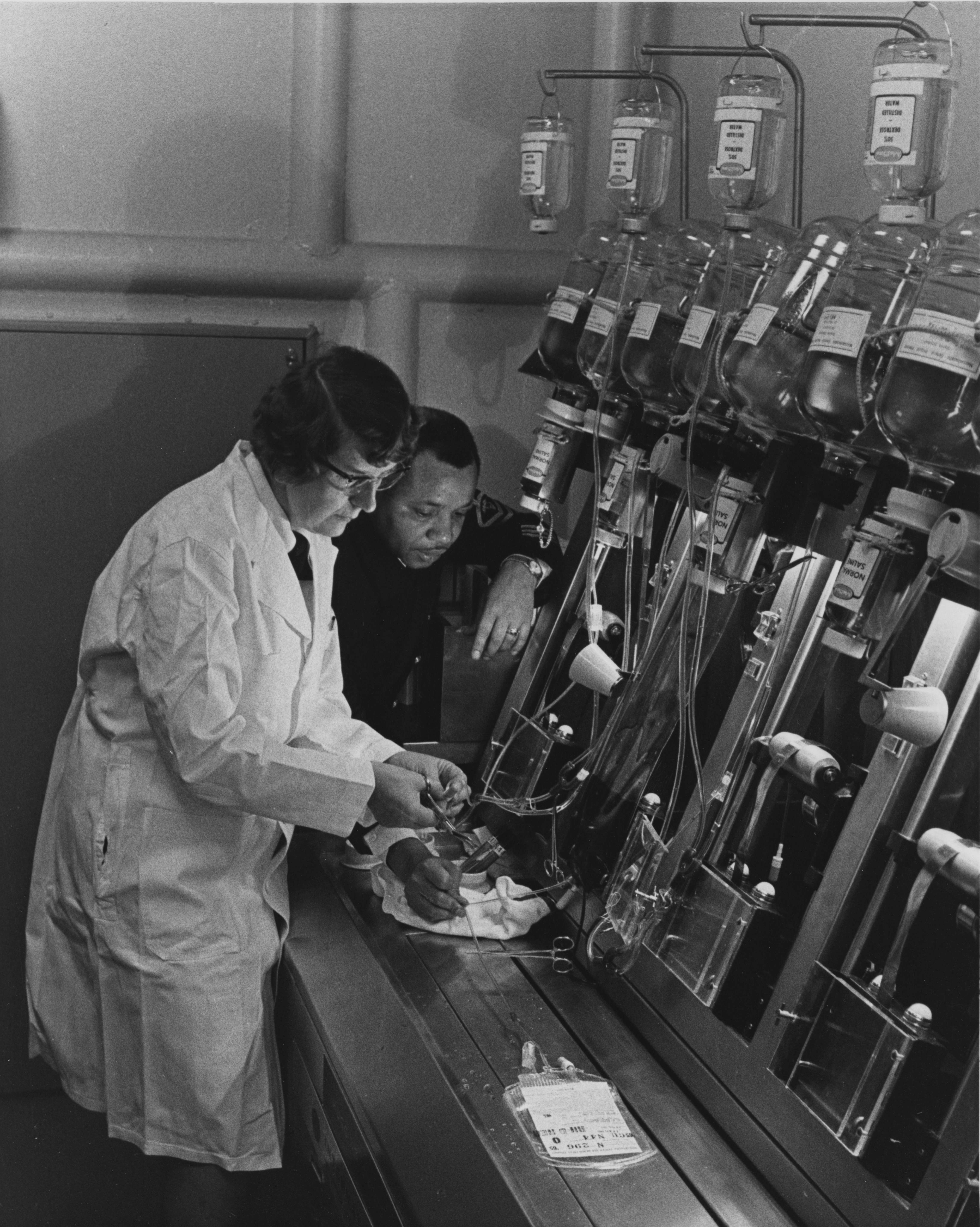 Zwei Personen arbeiten mit medizinischer Ausrüstung und Infusionsbeuteln