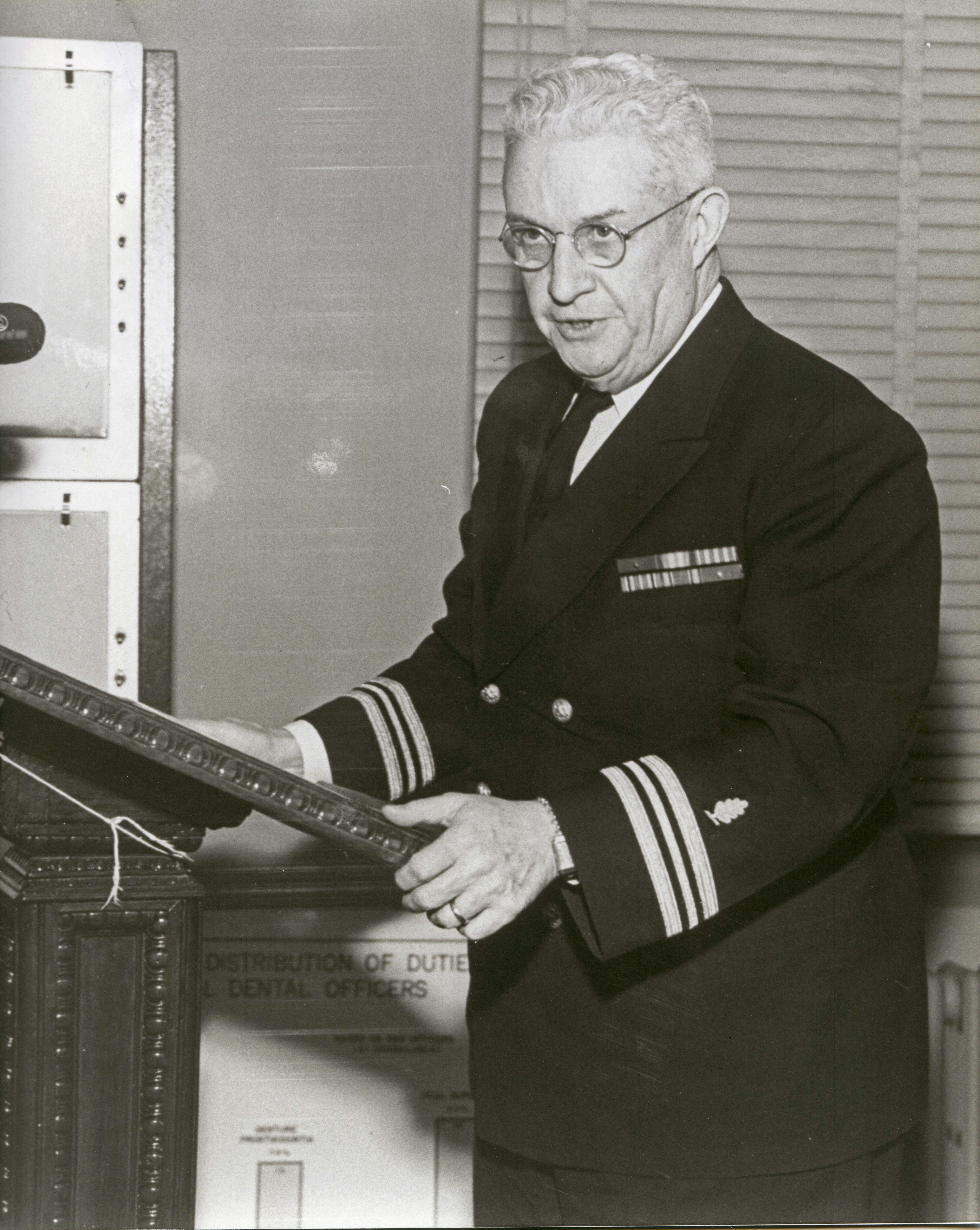 Hombre con uniforme naval de pie en un atril.