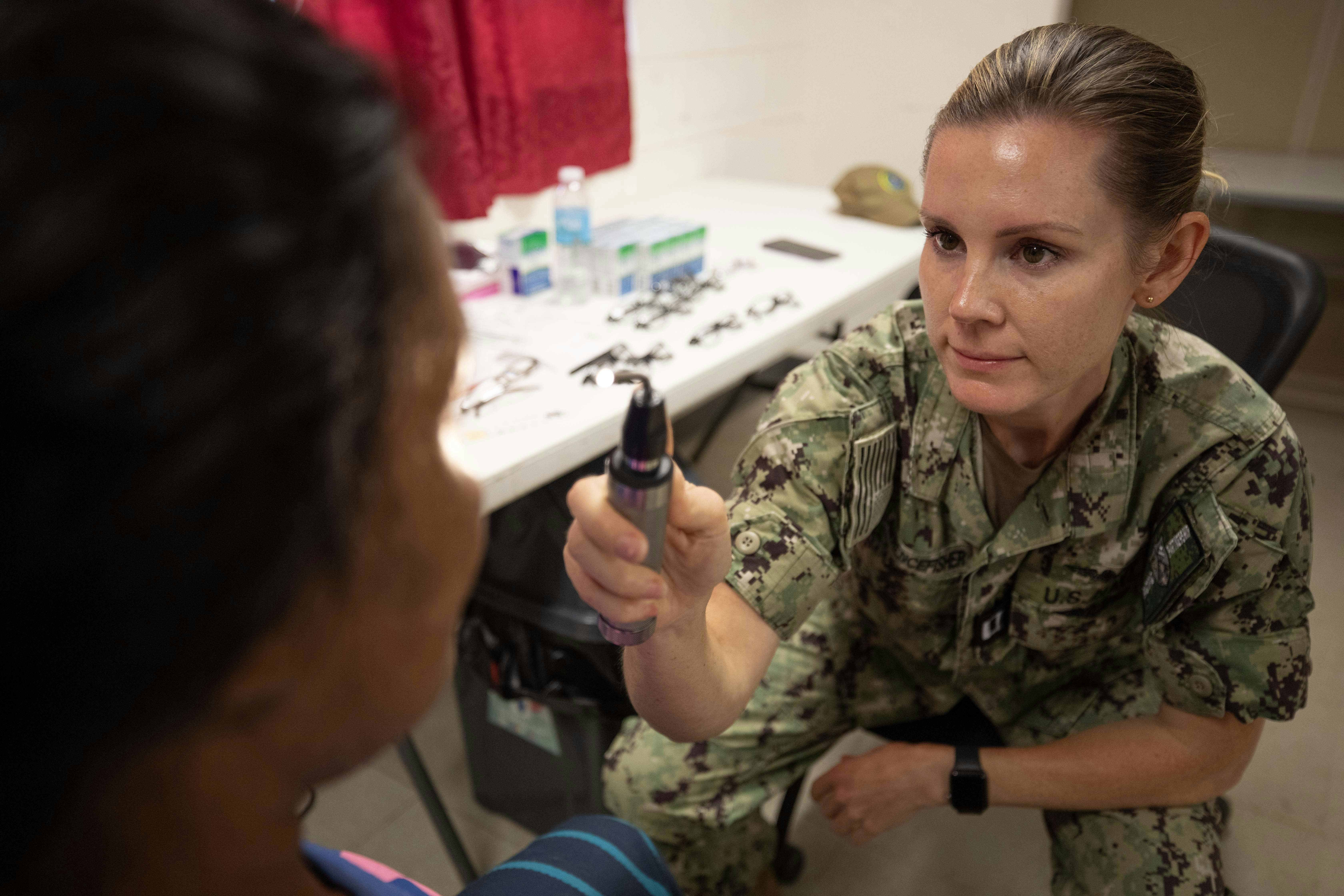 A medic examines a patient's eye with a light.