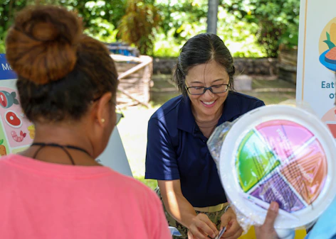A woman shows a colorful plate to another person.