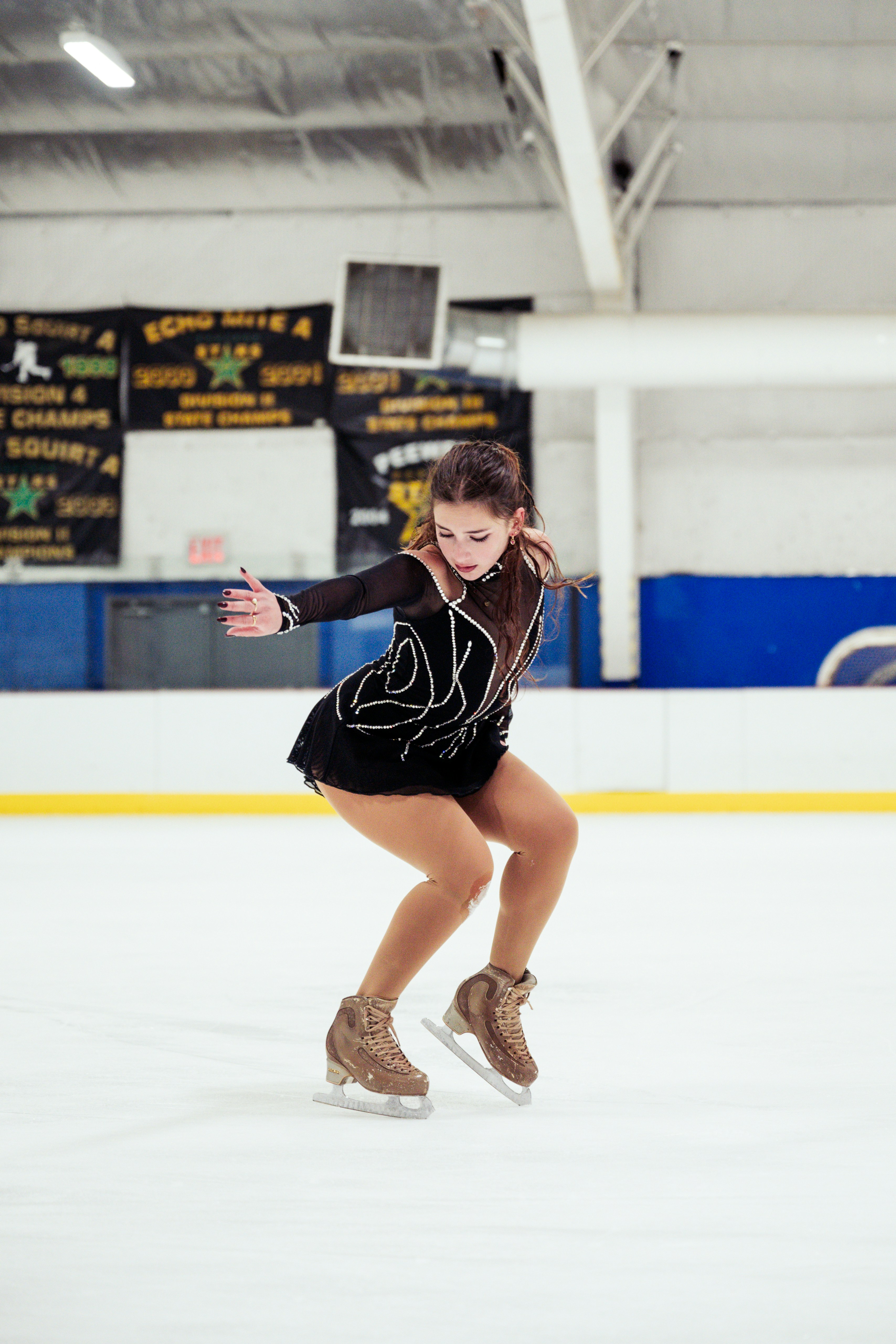 A young female figure skater performs on ice.