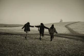 Three people running across a grassy field