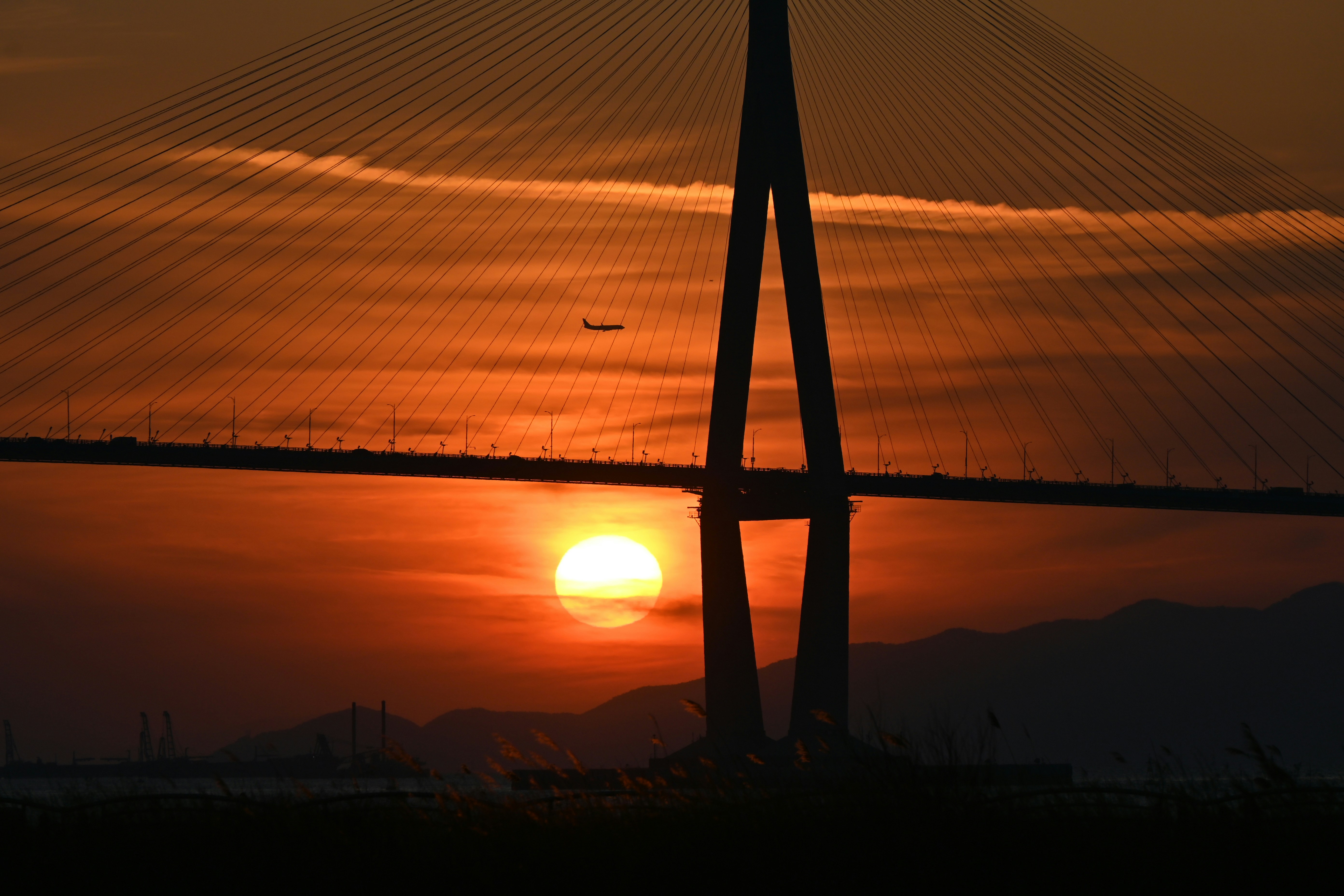 Bridge pylon silhouetted against a vibrant sunset