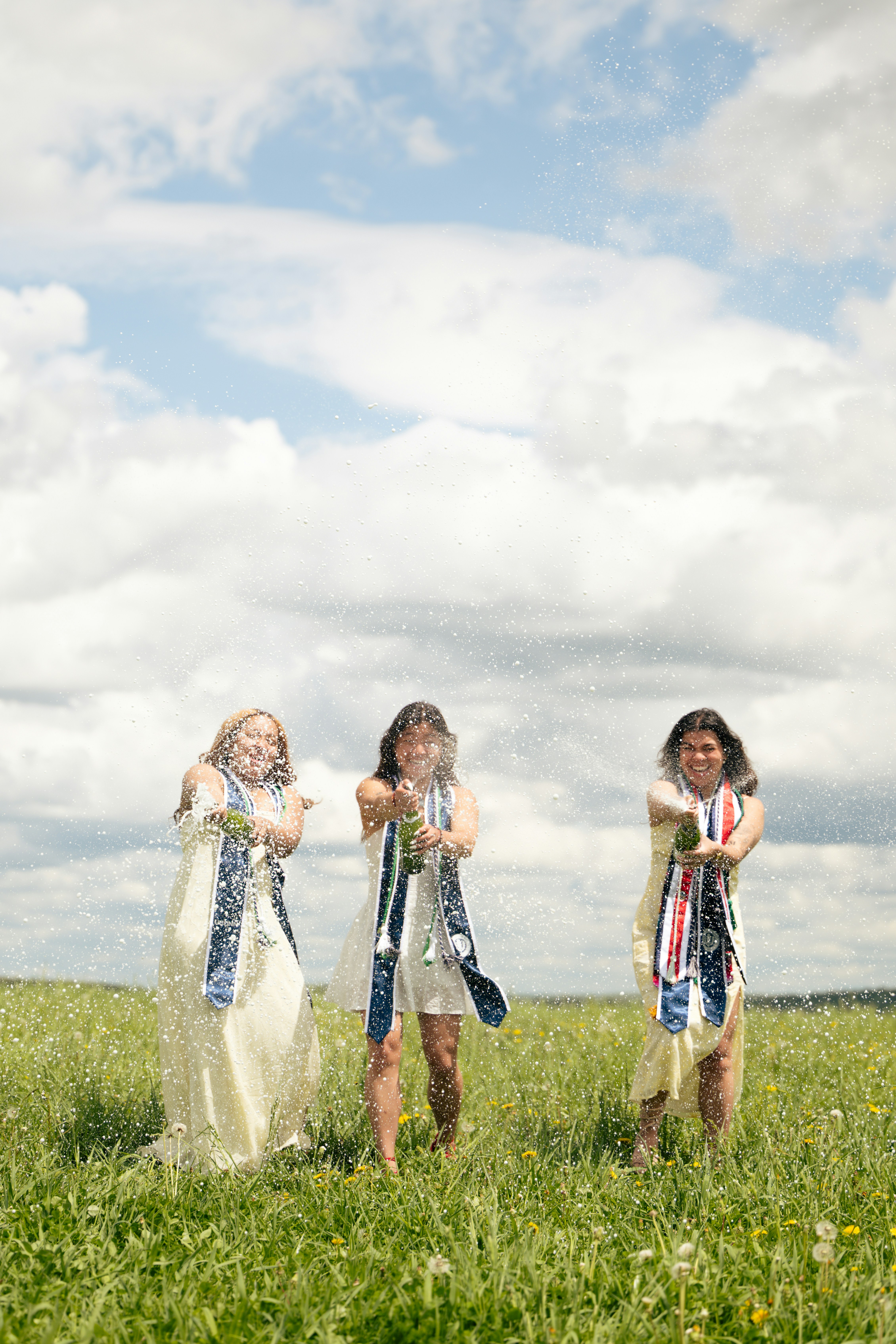 Three women spraying champagne in a field
