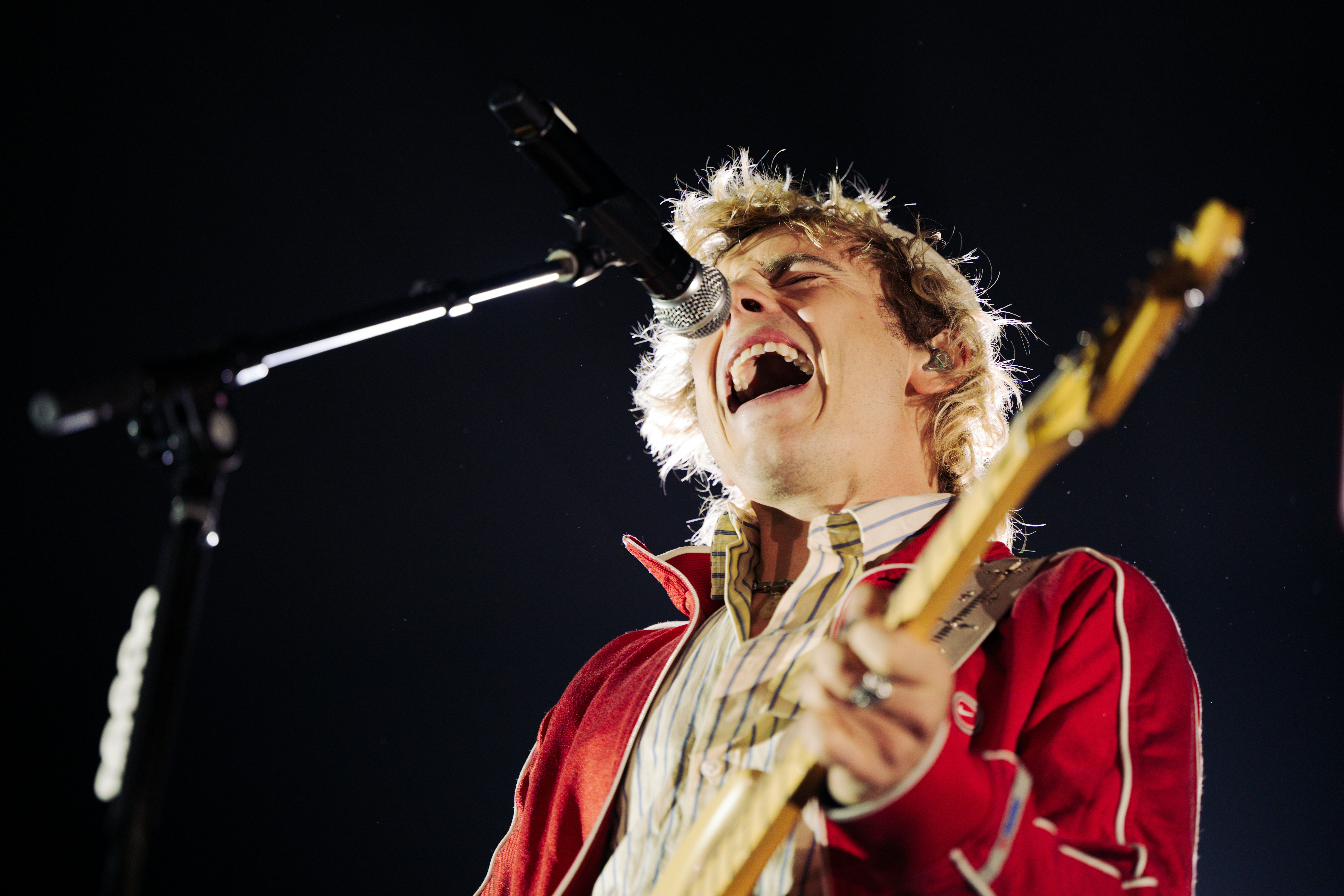 A male musician sings loudly while playing guitar