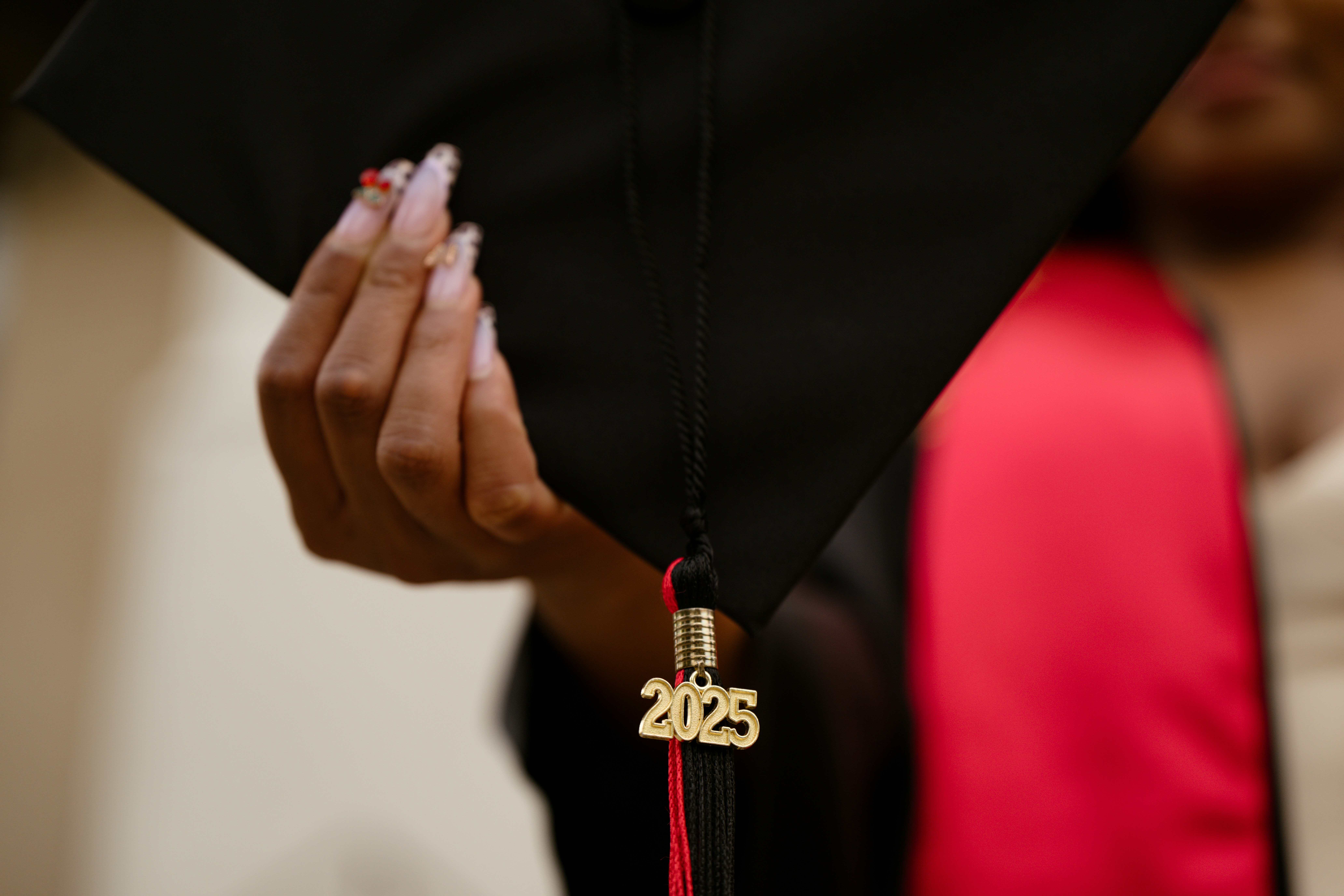 Graduation cap with 2025 tassel held by hand