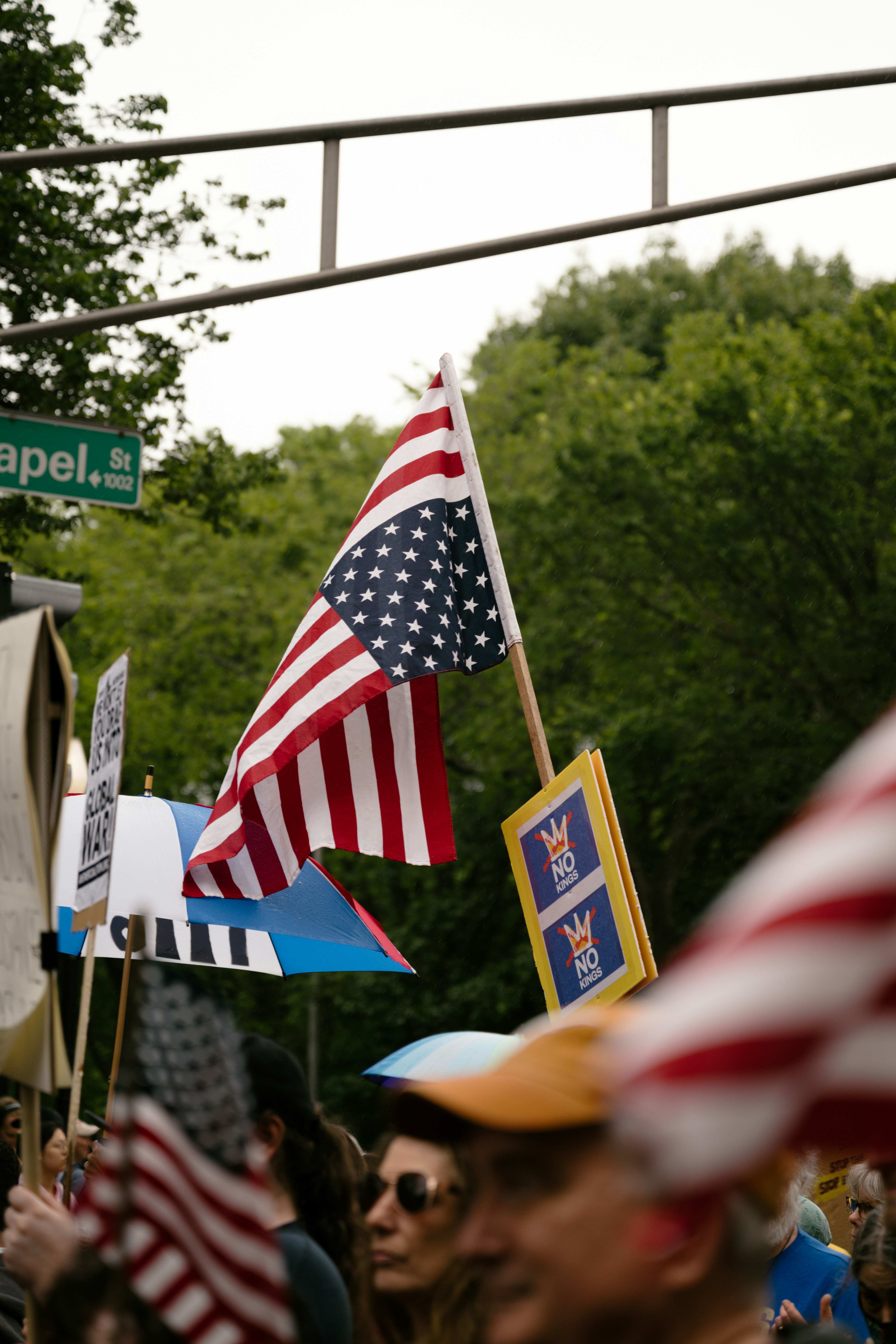 American flags waving at a rally with a street sign.