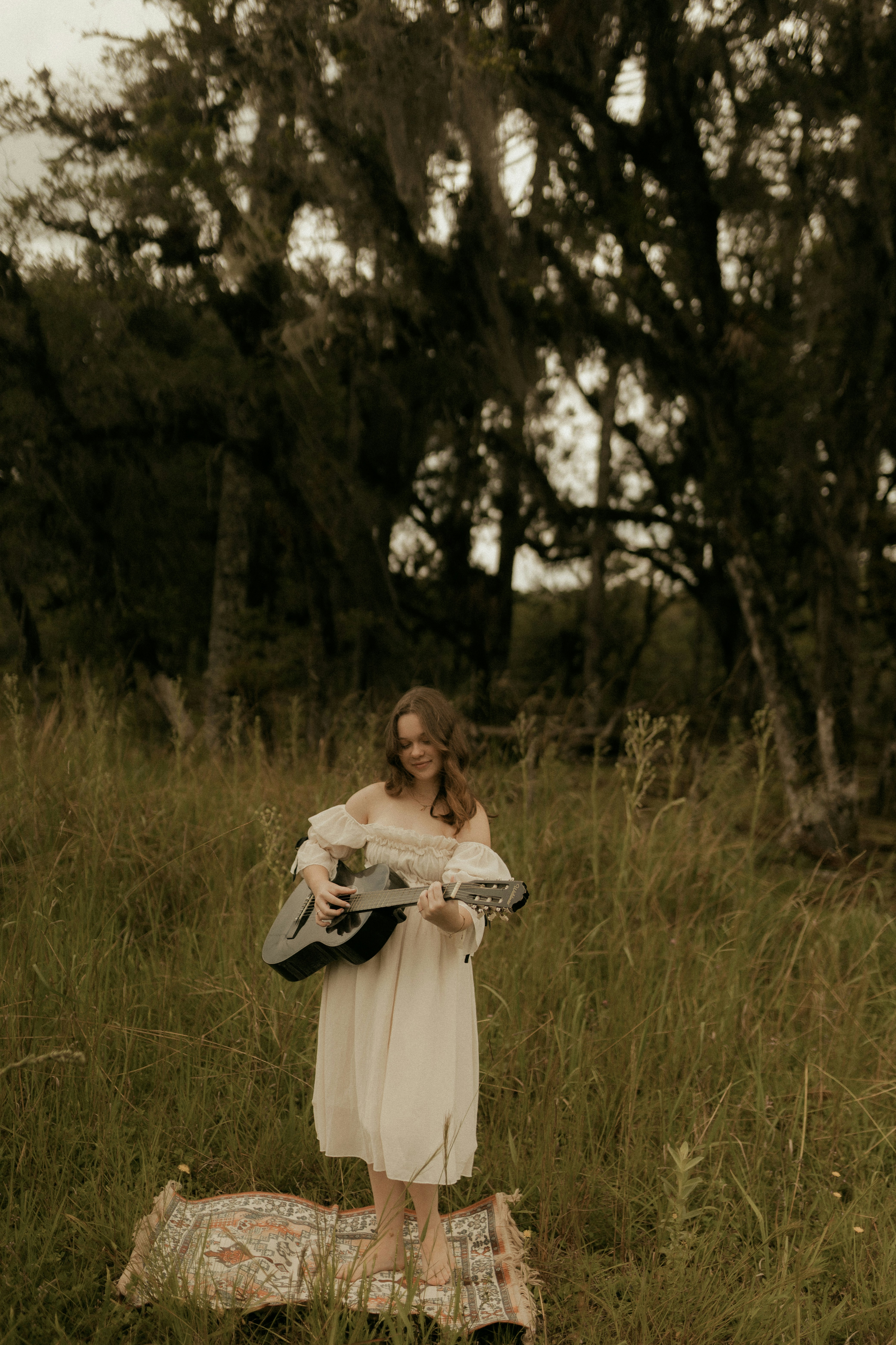 Young woman playing guitar in a grassy field