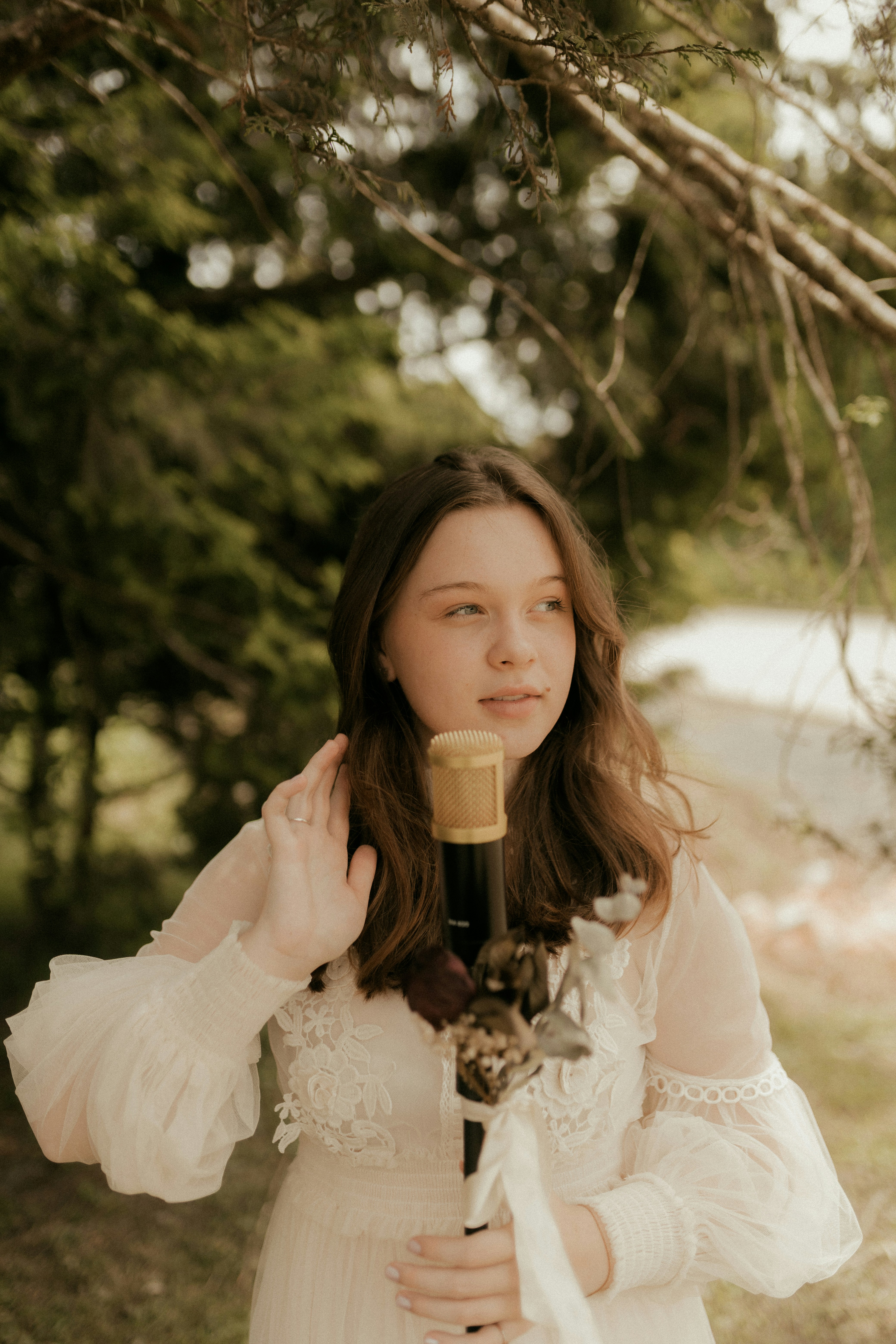 Young woman in white dress holding a microphone outdoors