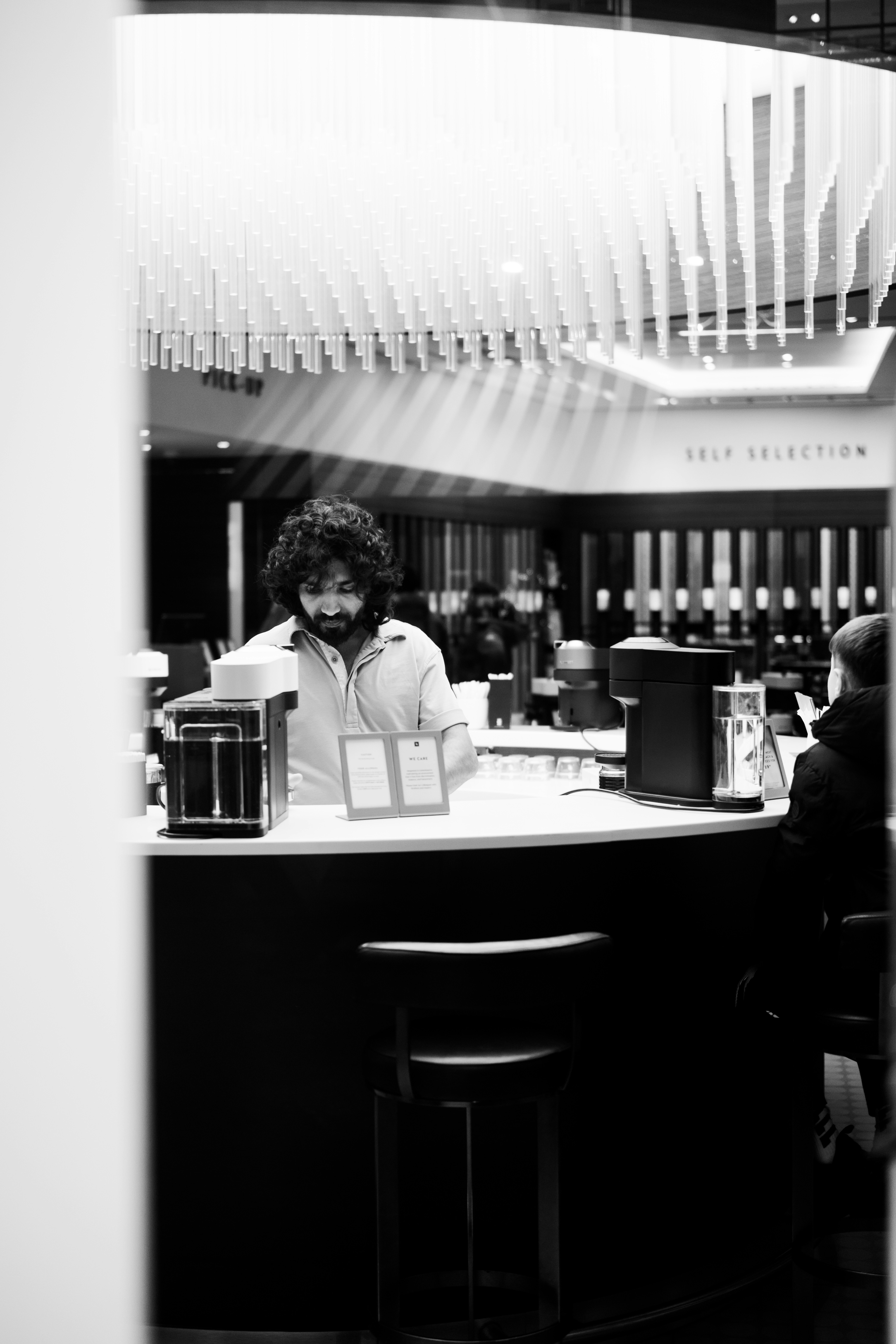 Man behind a bar with a modern light fixture.