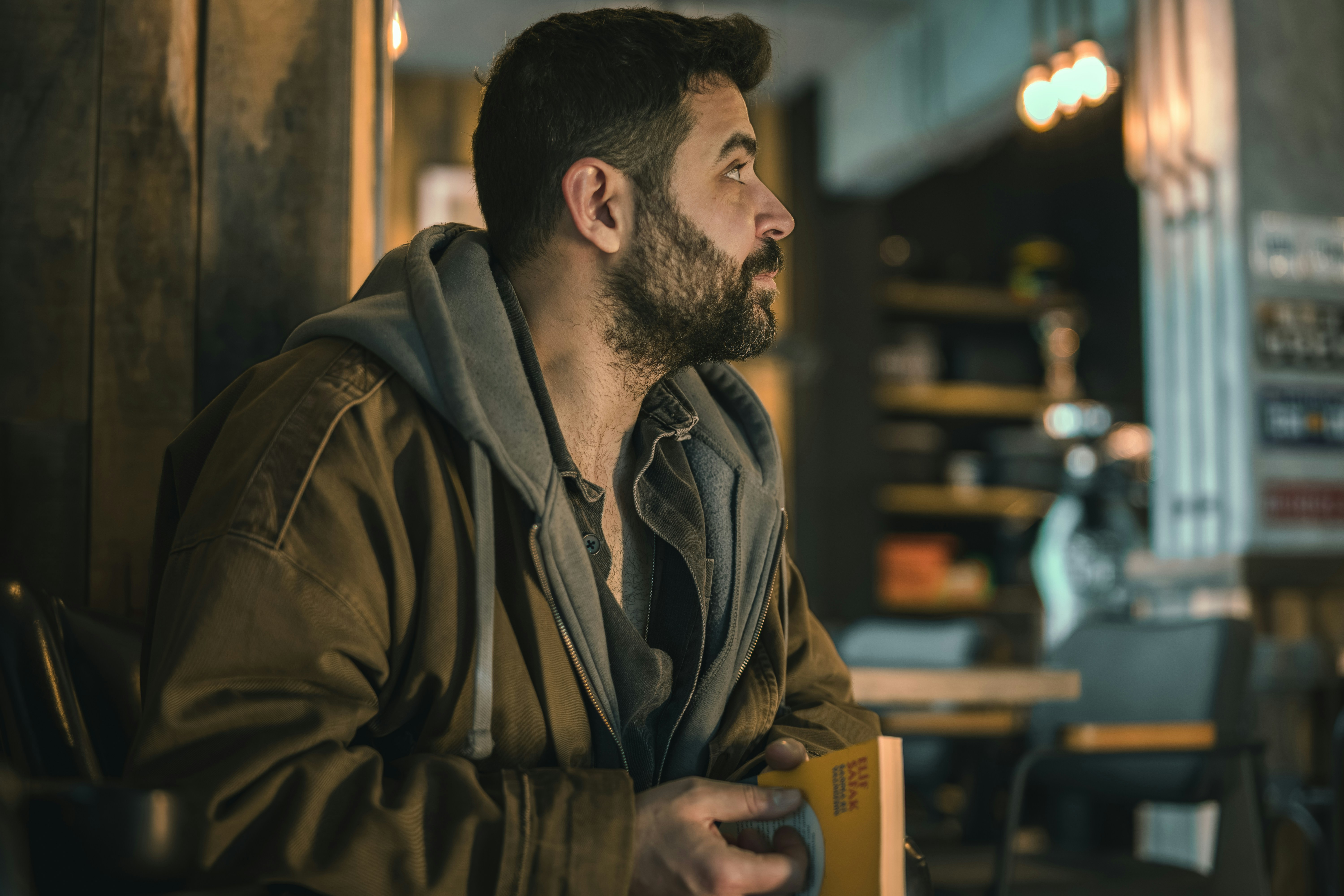 フード付きジャケットを着たひげの男が目をそらす。