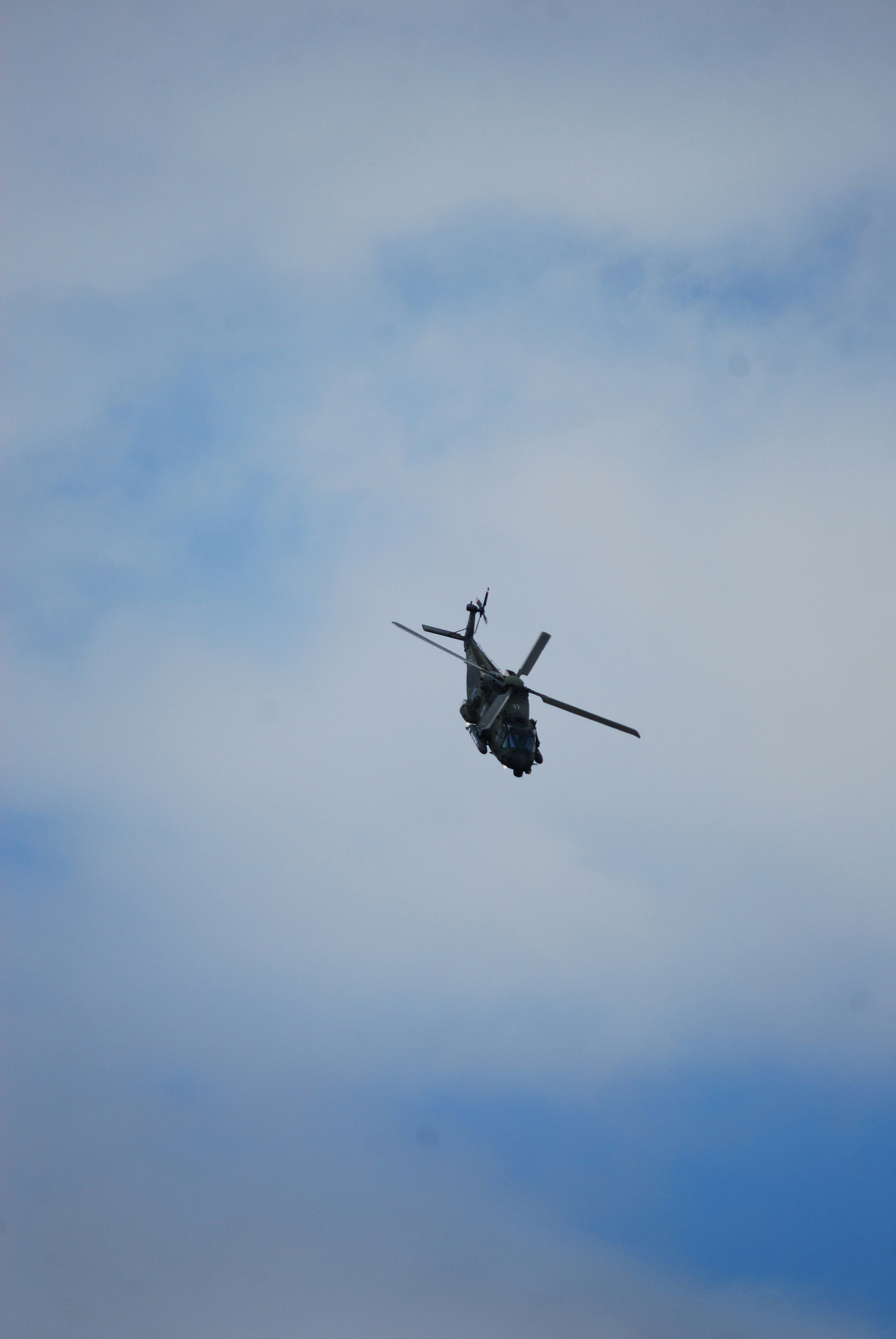 A helicopter flies in a cloudy sky