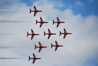Nine red and white jets fly in formation in TEAMWORK.
