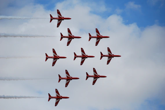 Nine red and white jets fly in formation in TEAMWORK.