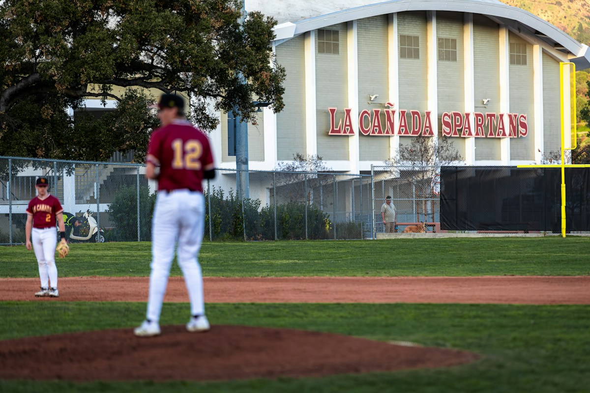 Youth baseball players on a field with a stadium backdrop, illustrating youth sports coordination in action.