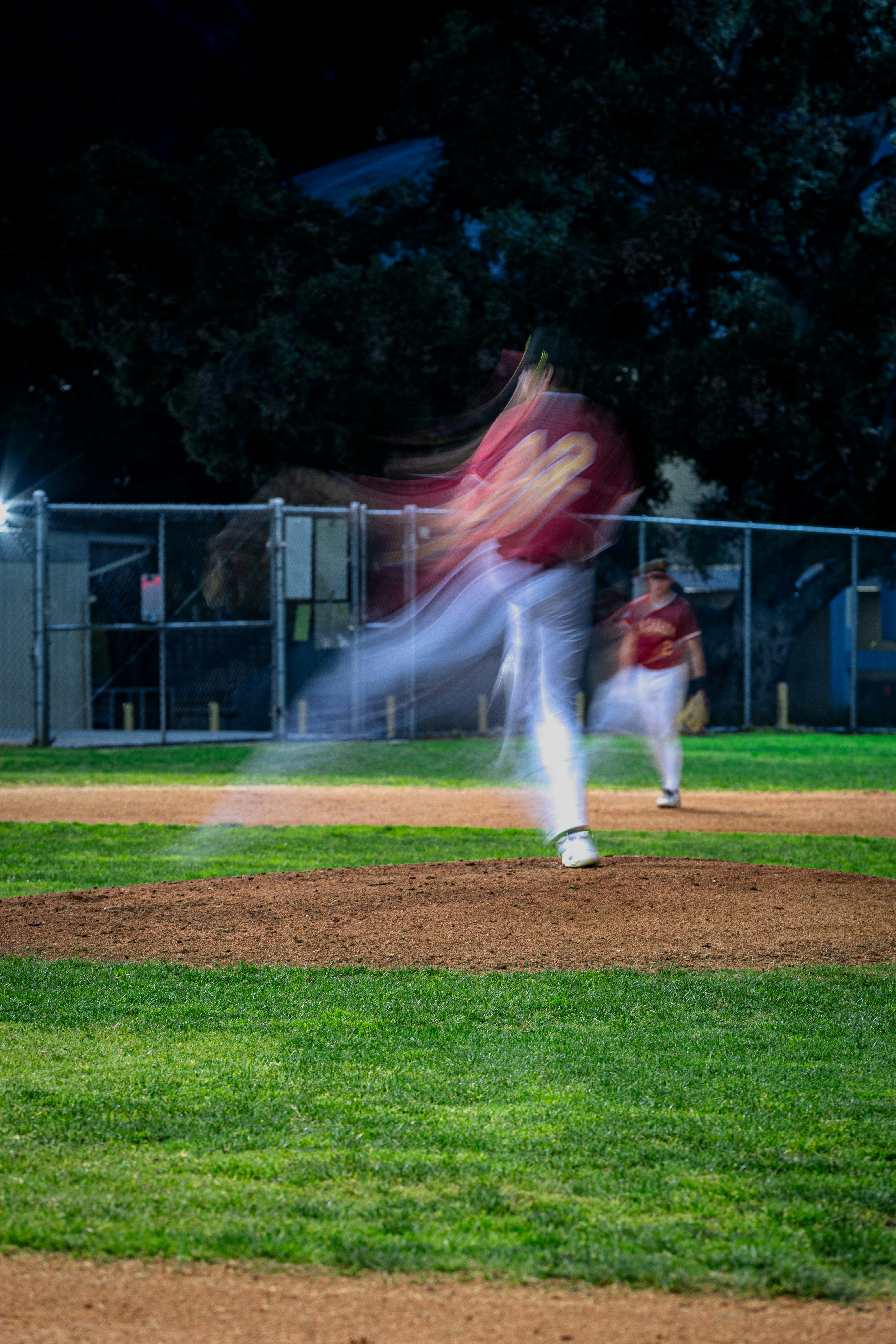 Lanzador de béisbol en movimiento en el montículo por la noche