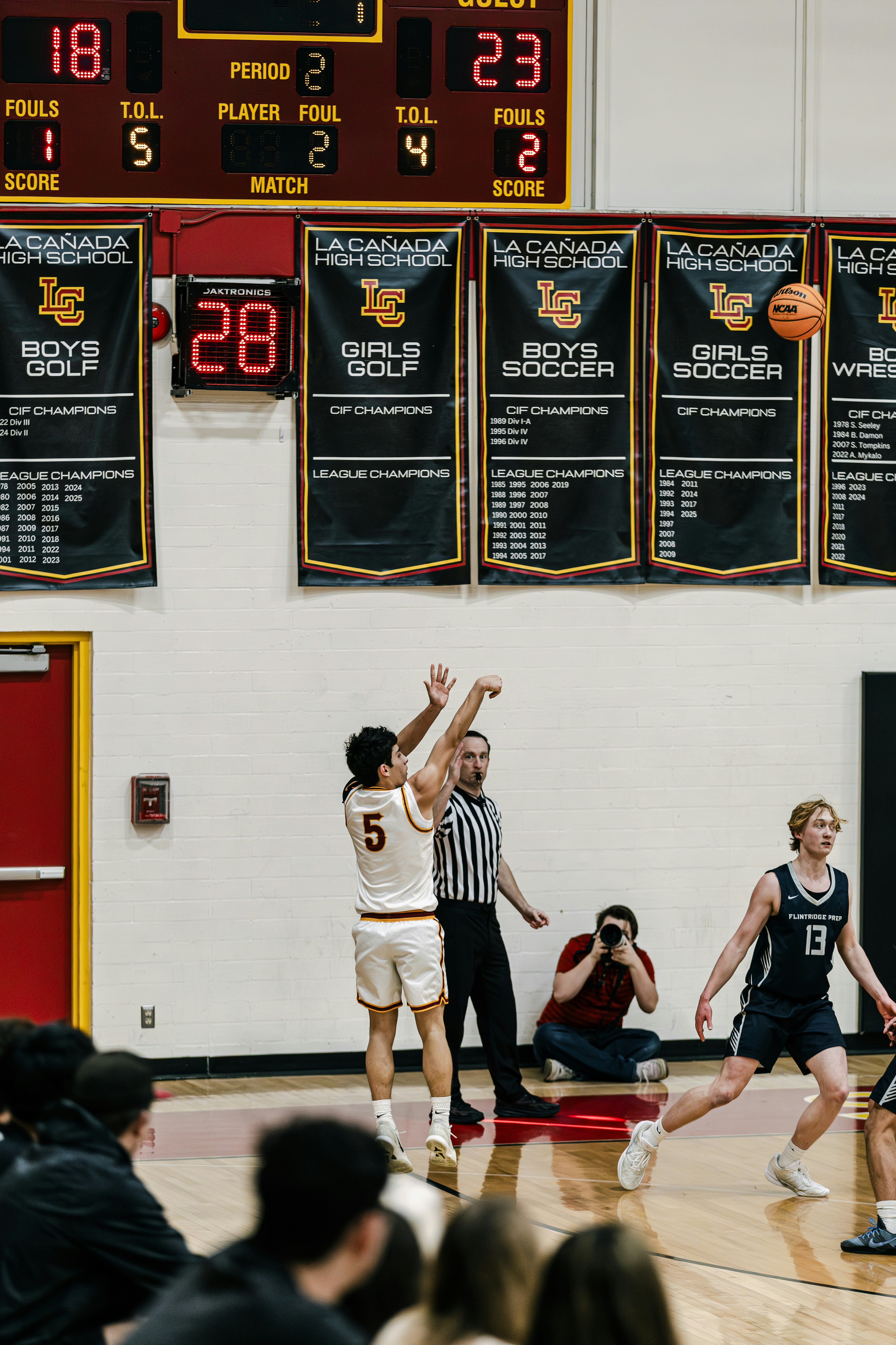 バスケットボール選手が審判や観客の近くでシュートを放つ。