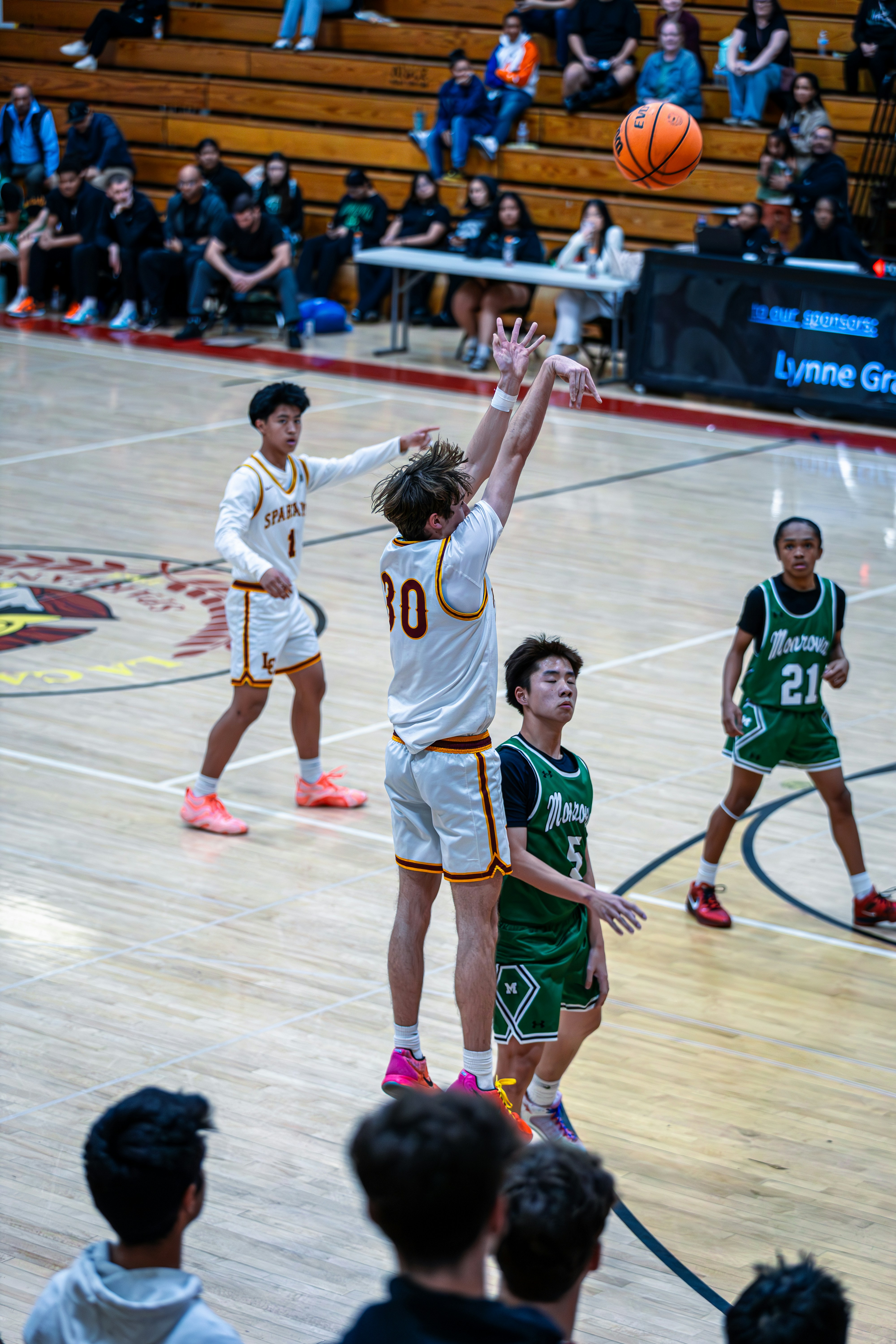 試合中にバスケットボールをシュートしているティーンエイジャー。