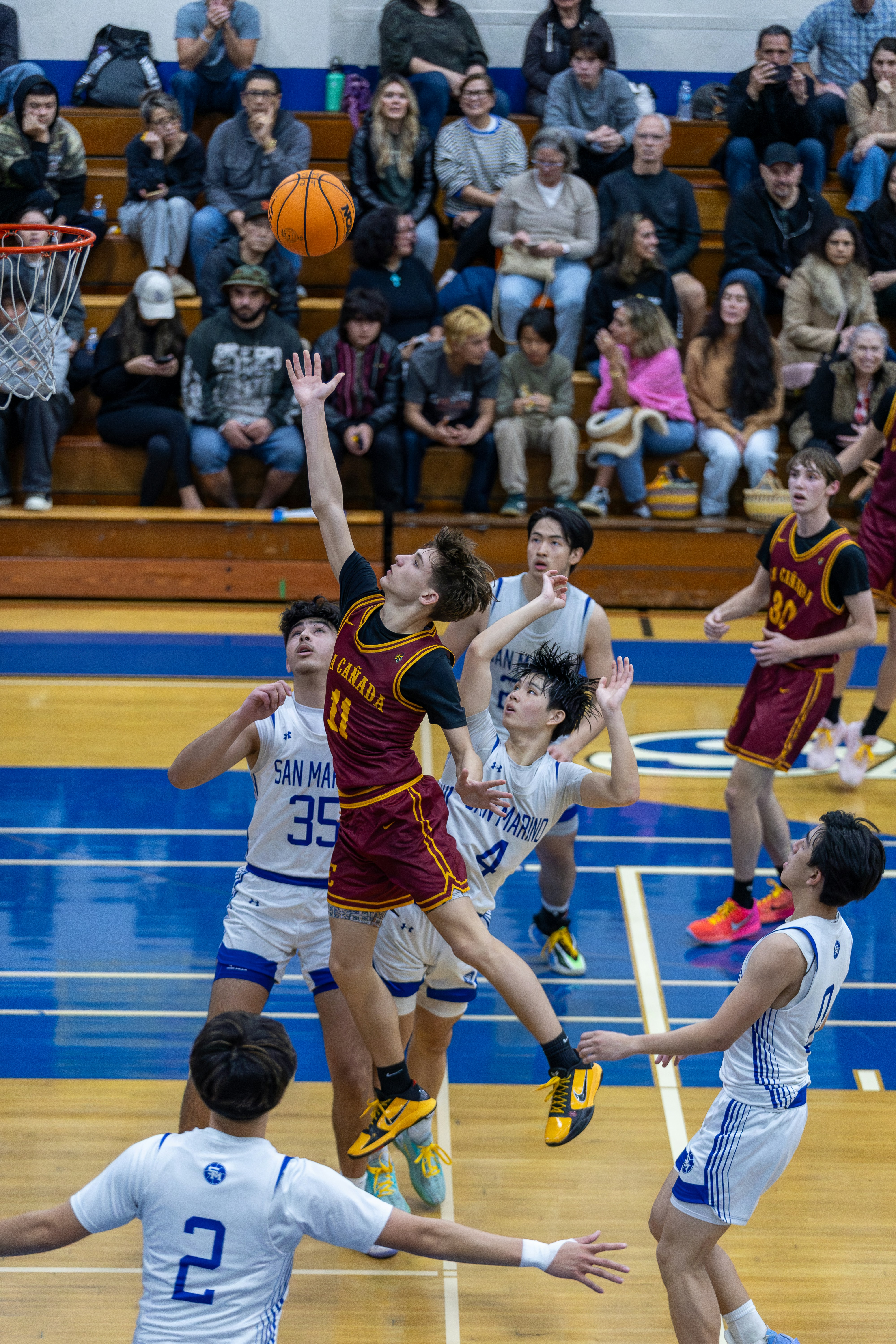 バスケットボール選手が試合中にボールを飛び跳ねる様子。