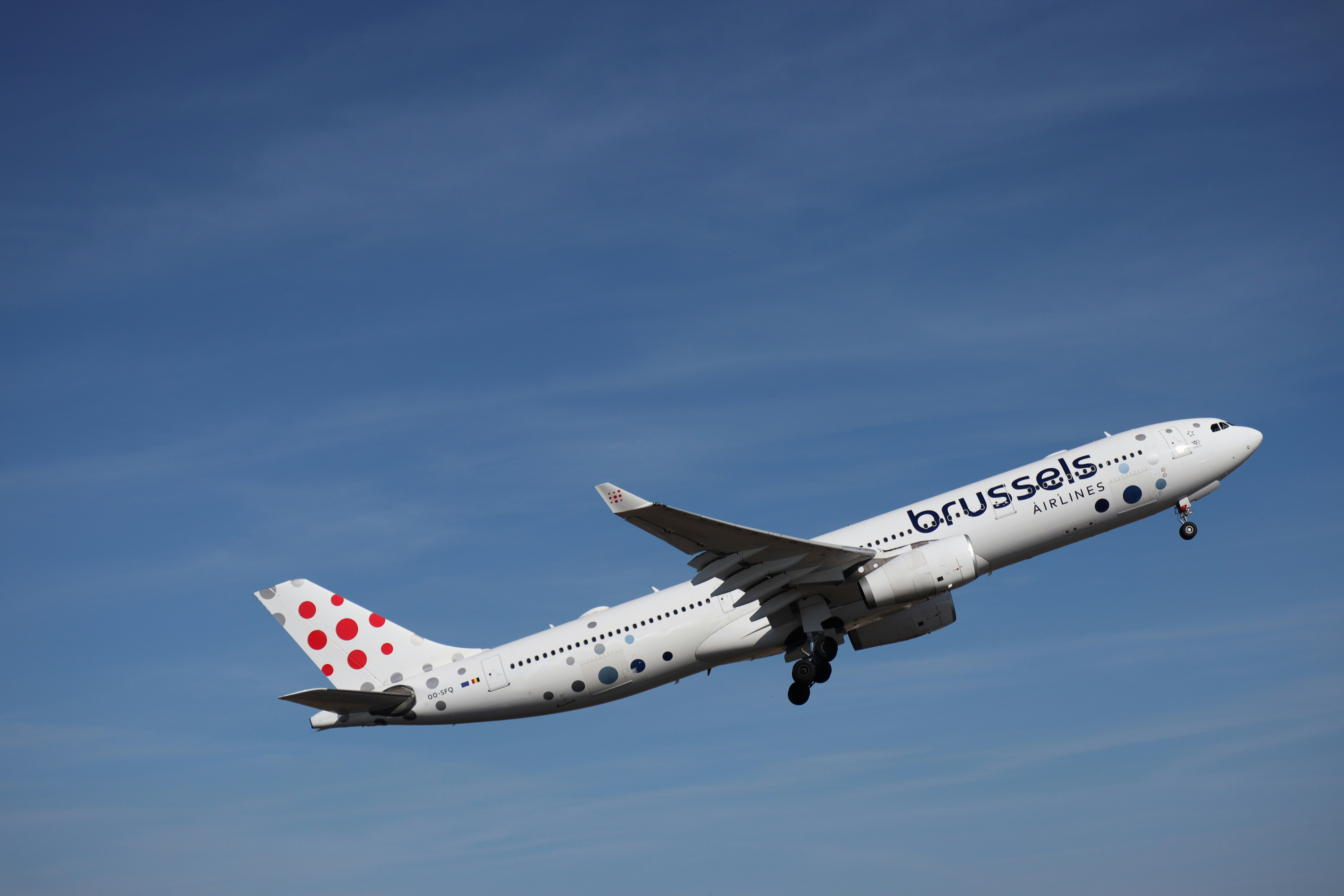 A commercial airplane takes off against a blue sky