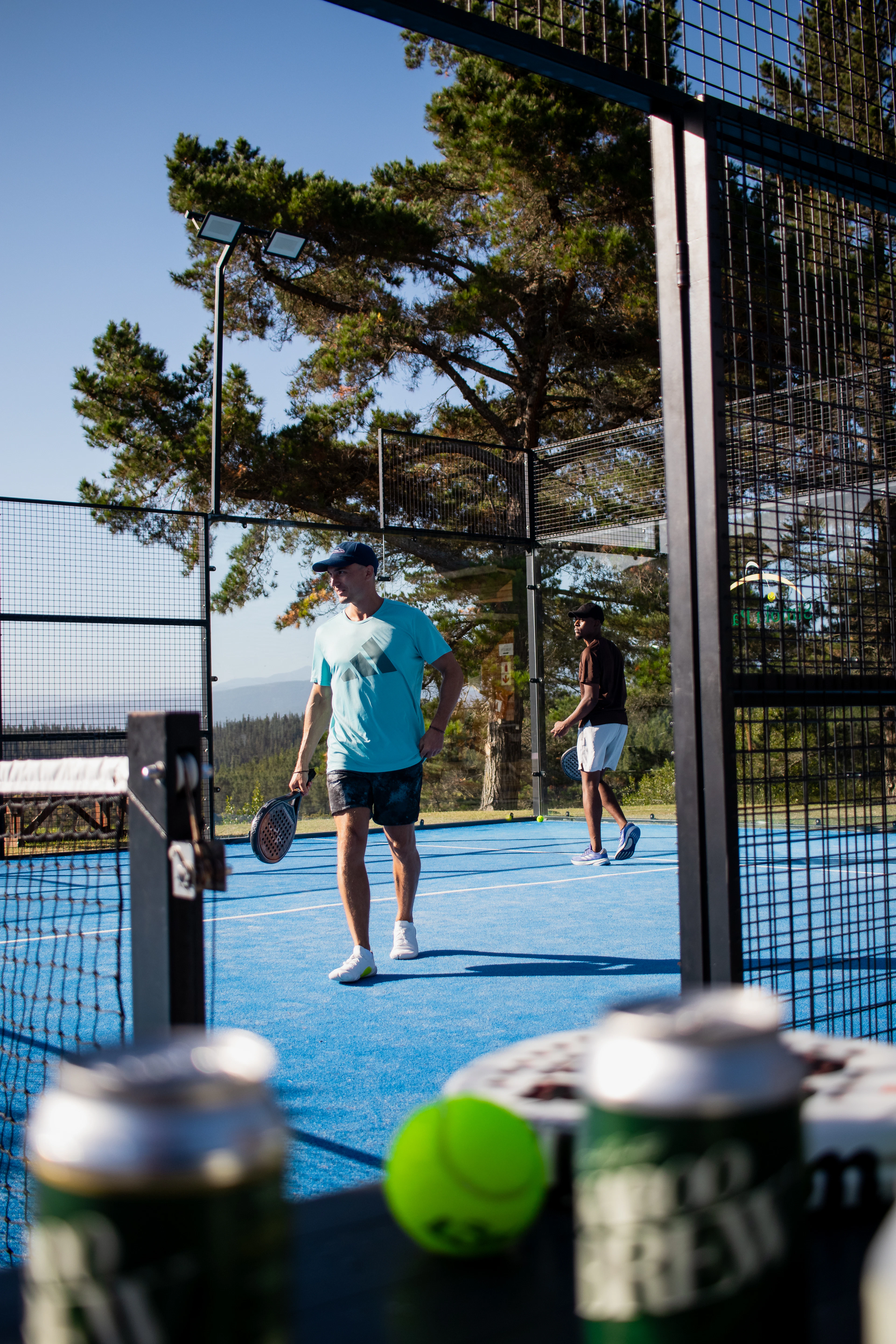 Dos jóvenes jugando al pádel en una pista azul