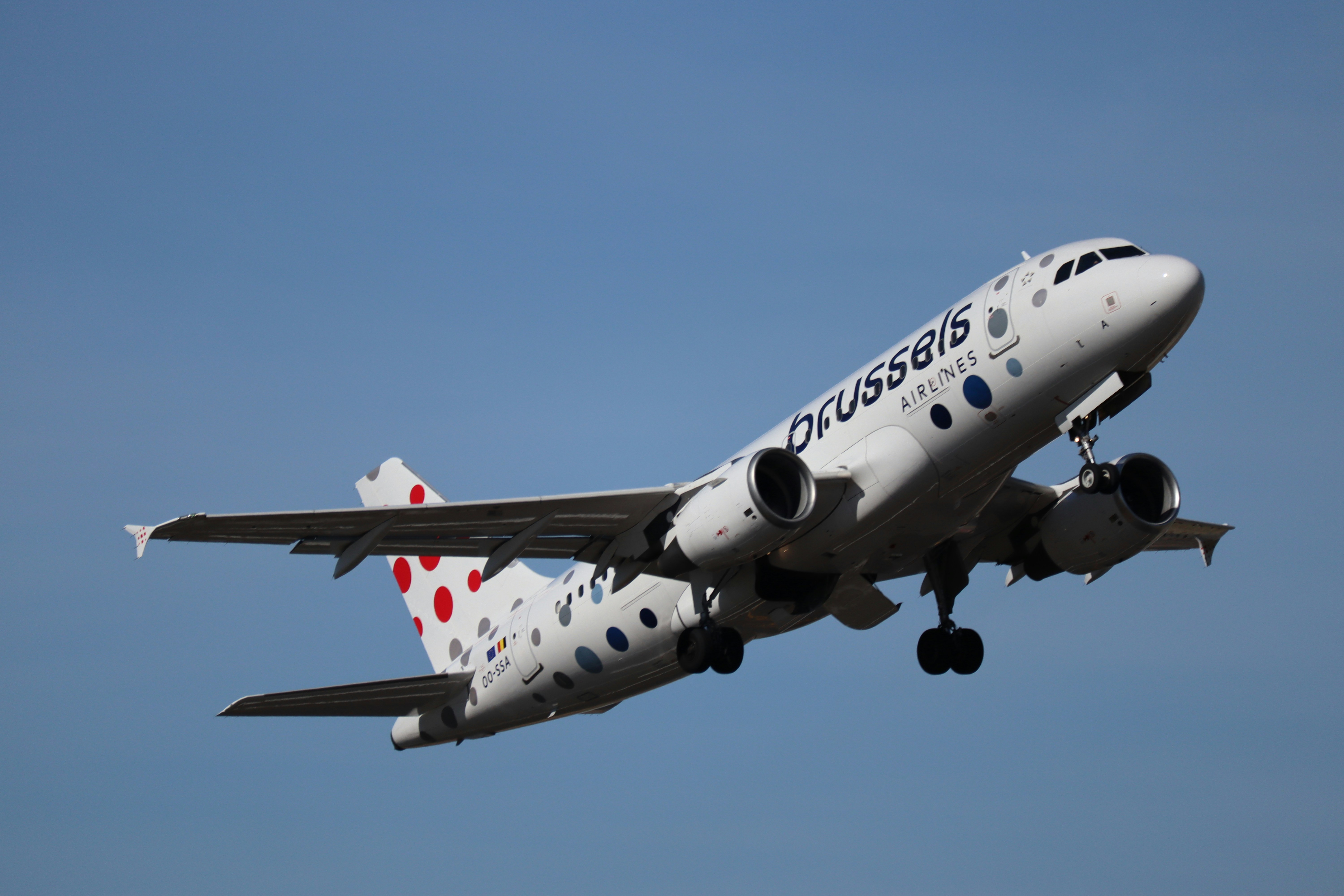 A white airplane with red polka dots takes off.