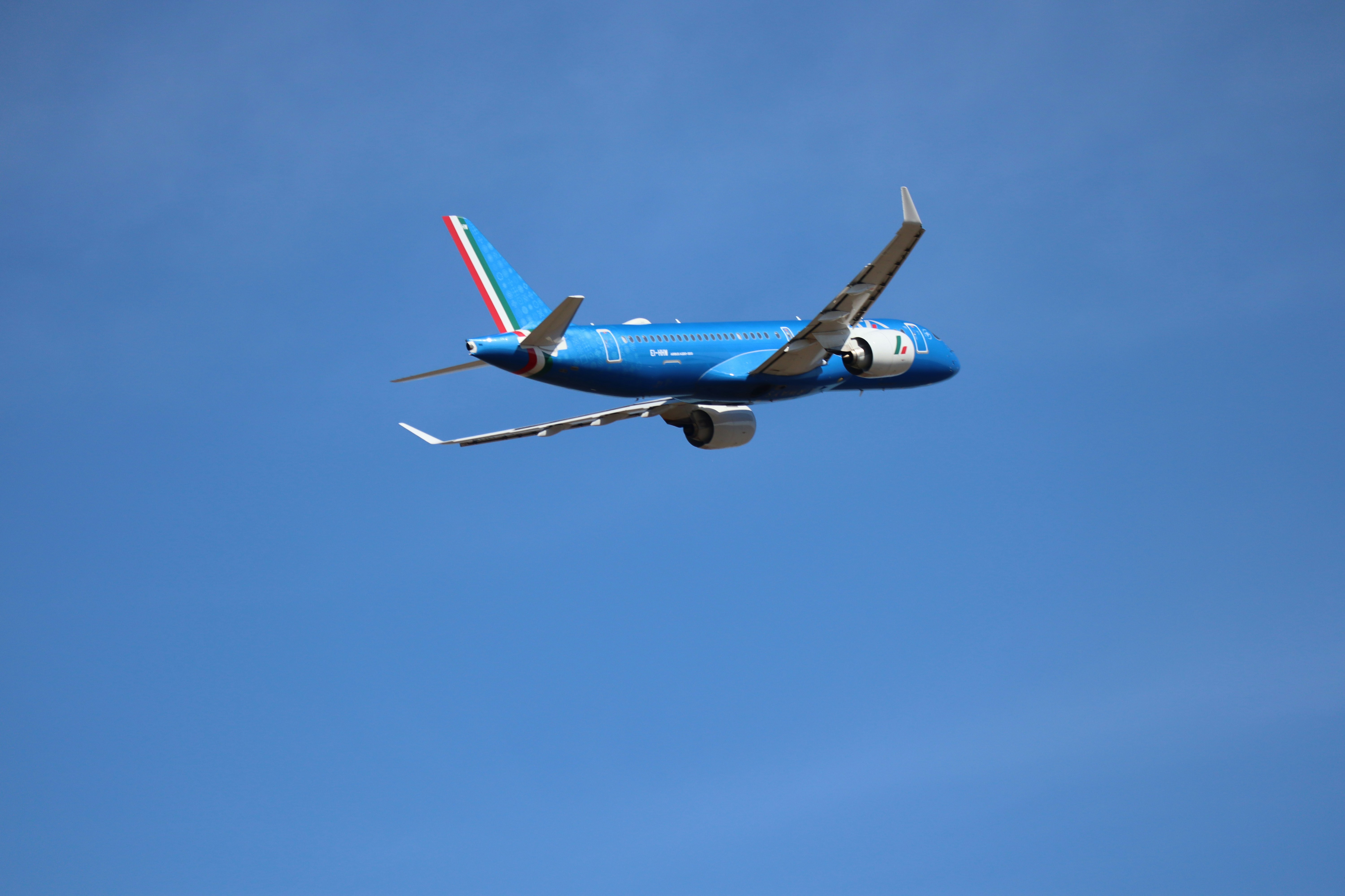 A blue airplane flying in a clear sky