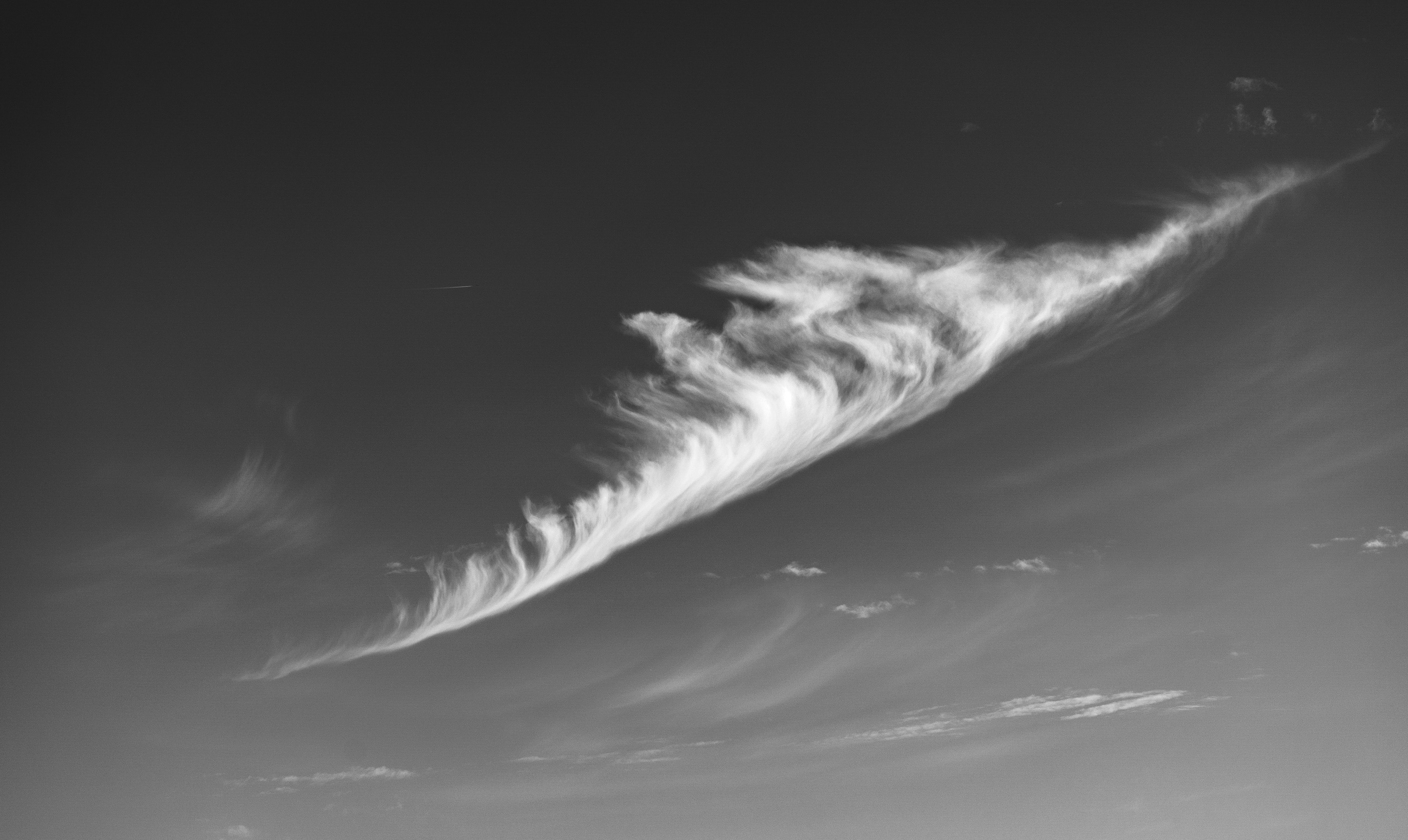 A single wispy cloud formation against a dark sky