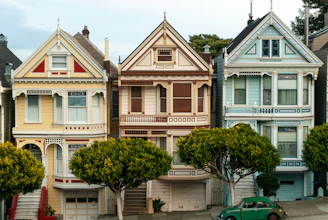 Row of colorful victorian houses with green car.