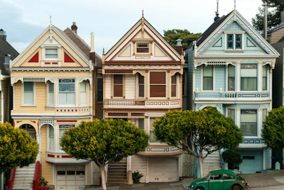 Row of colorful victorian houses with green car.