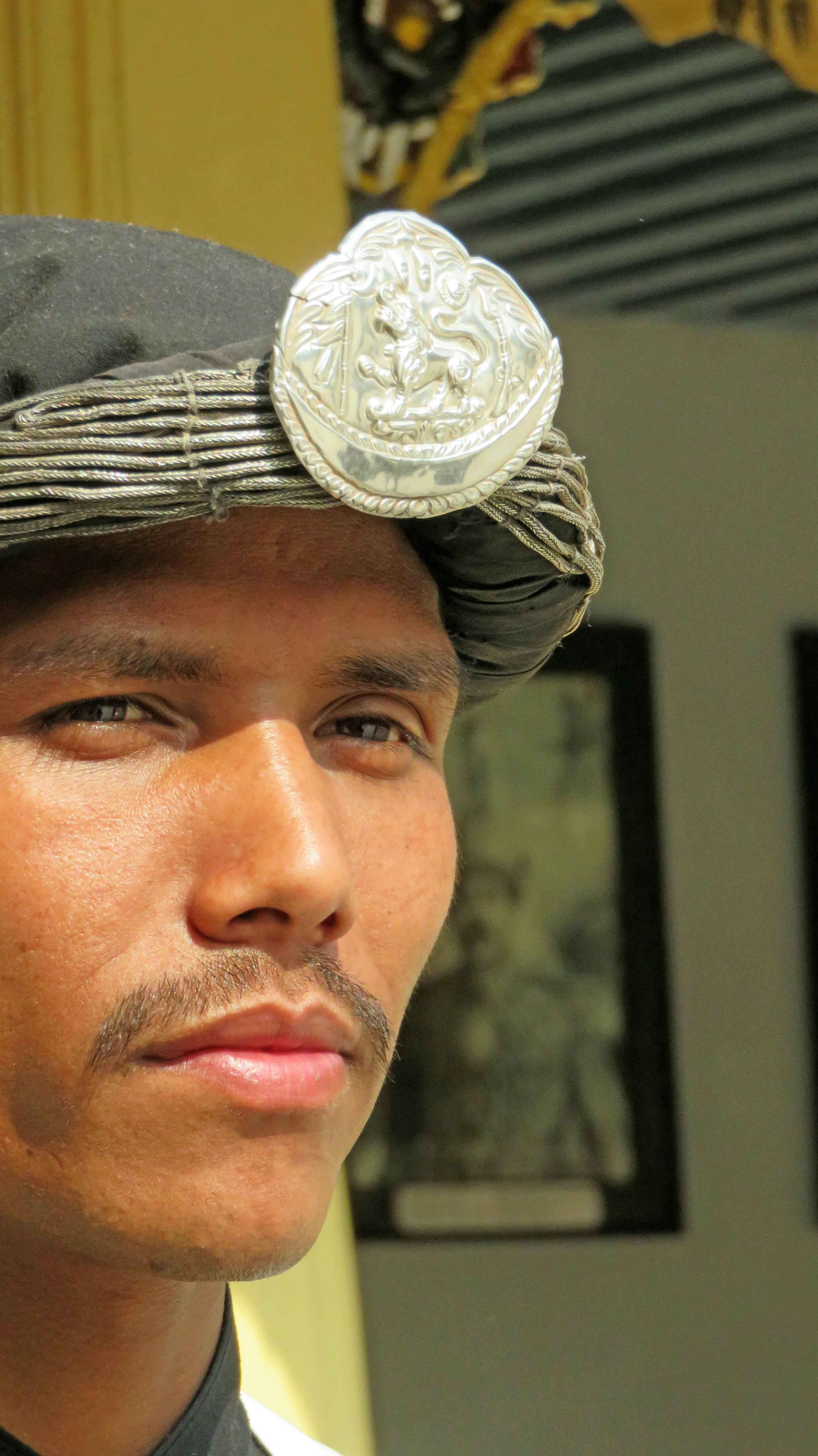 Homem usando um turbante tradicional com um emblema prateado.