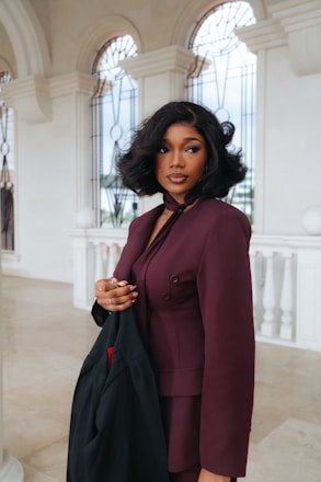 A woman in a maroon suit holding a black jacket.