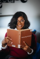 A smiling woman holds a book titled understanding fiction.