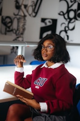 A young woman wearing glasses reads a book.