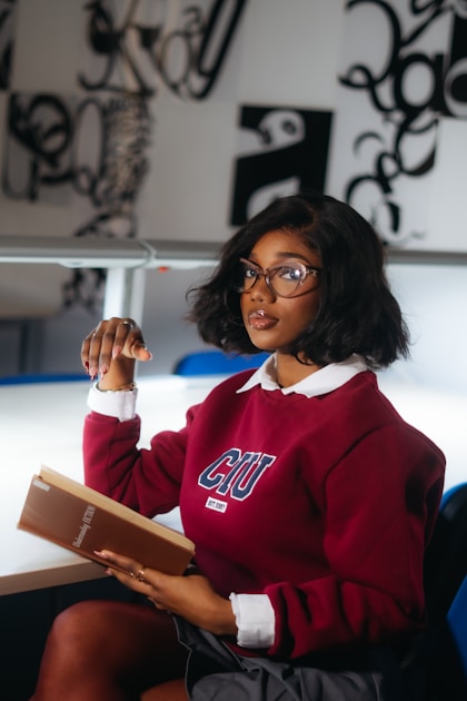 A young woman wearing glasses reads a book.