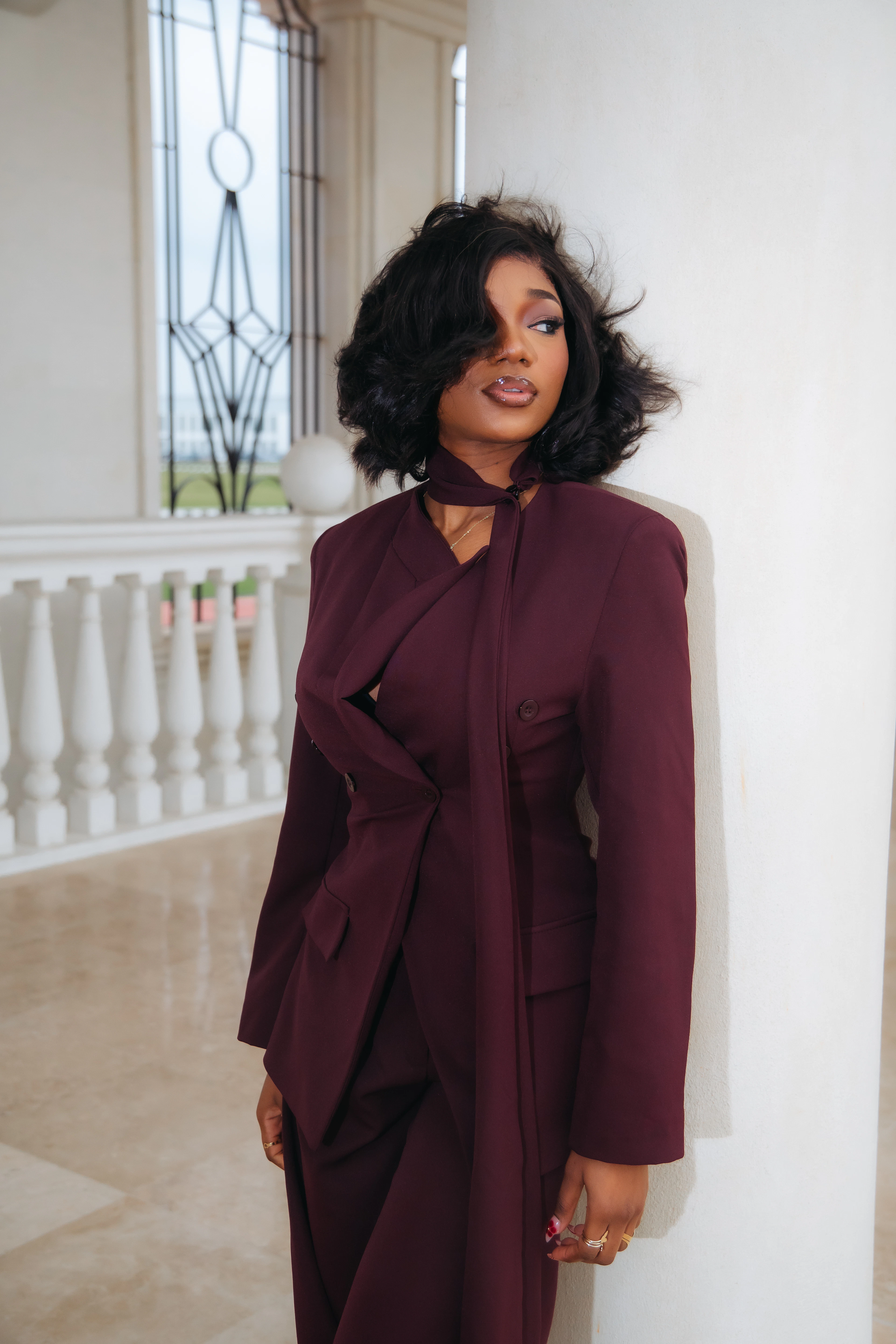 Model in a burgundy tailored suit with a scarf neckline