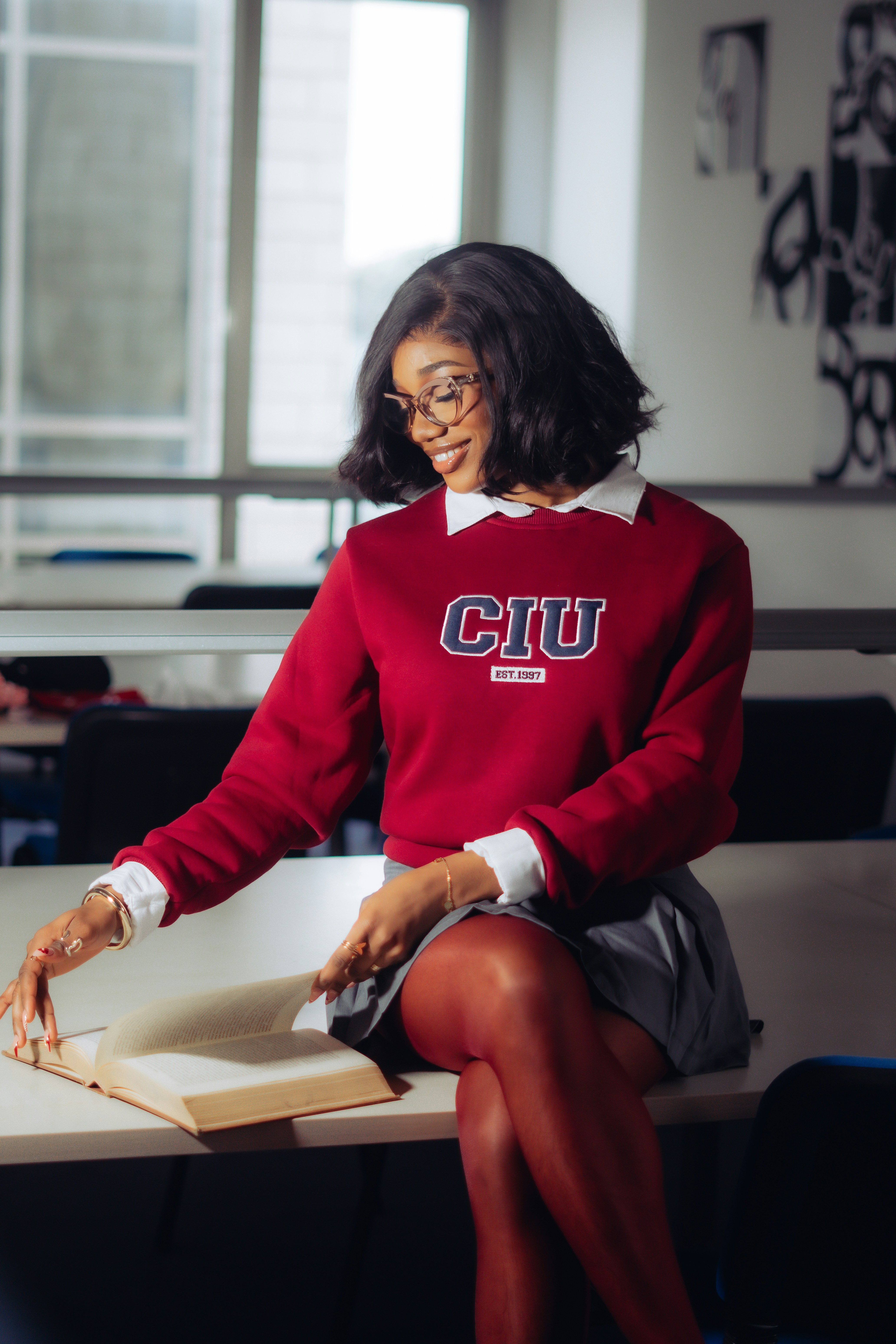 A young woman in a classroom with a book.