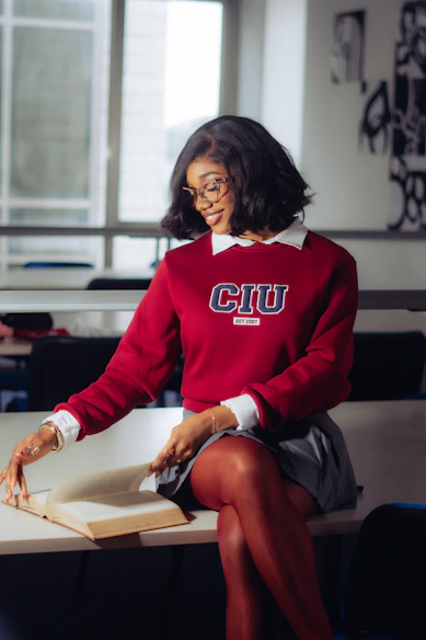 A young woman in a classroom with a book.