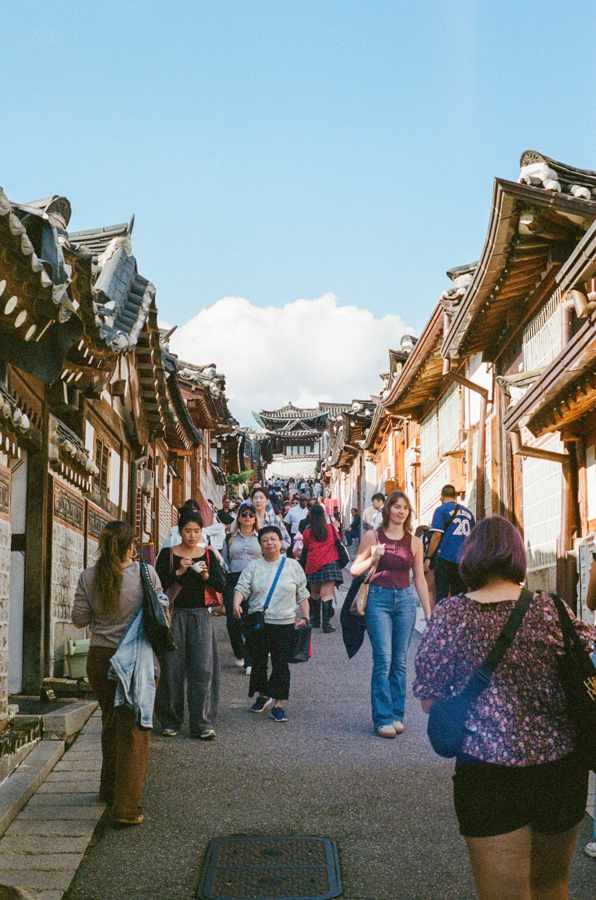 群衆は伝統的な建物が並ぶ狭い通りを歩いています。