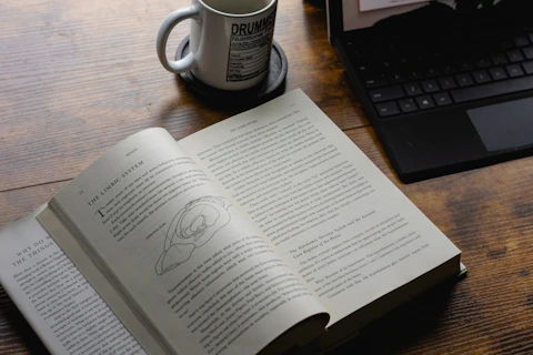 An open book with a coffee mug and laptop.
